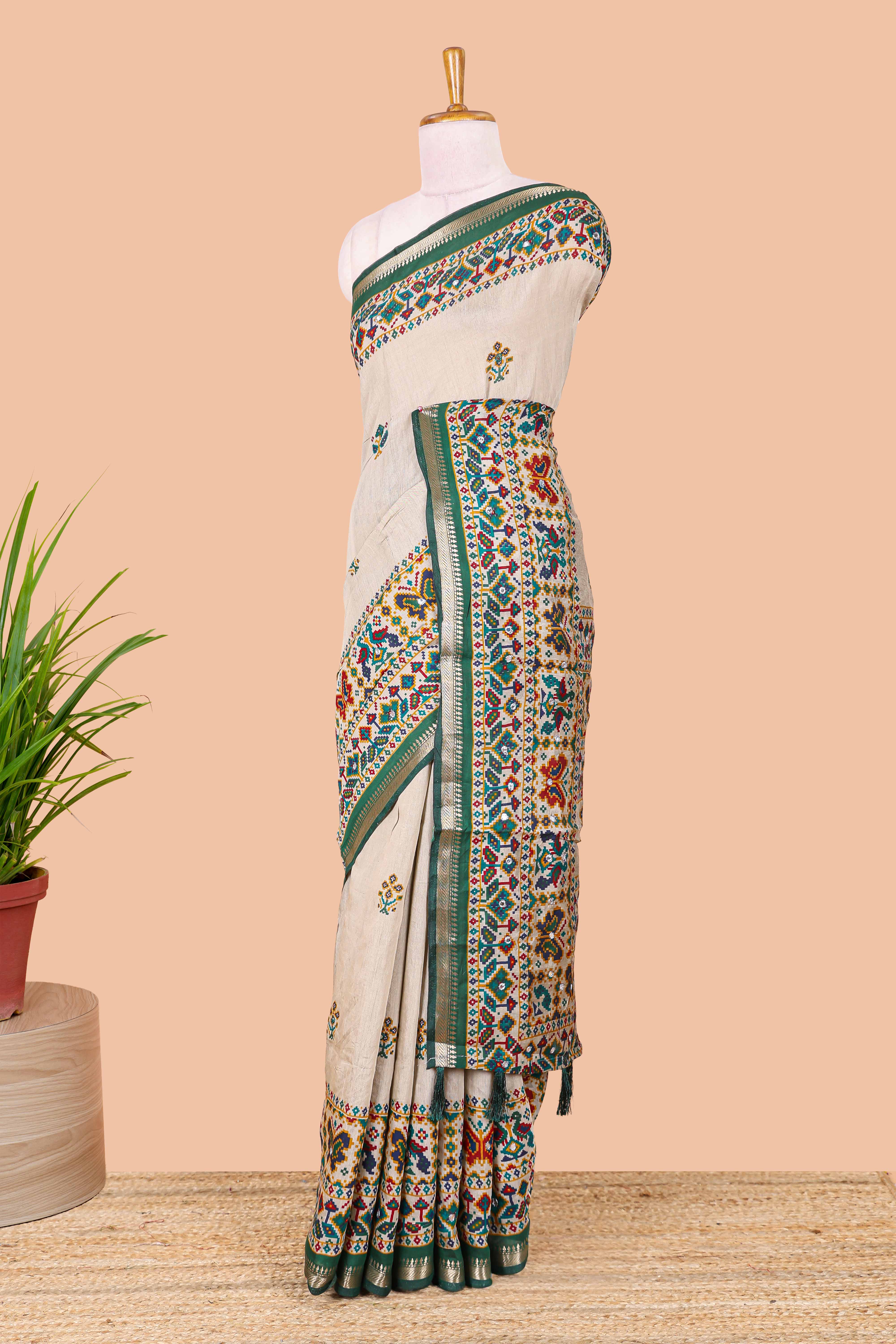 Cream chanderi cotton saree with geometric floral butta, green zari border and patola inspired mirror work