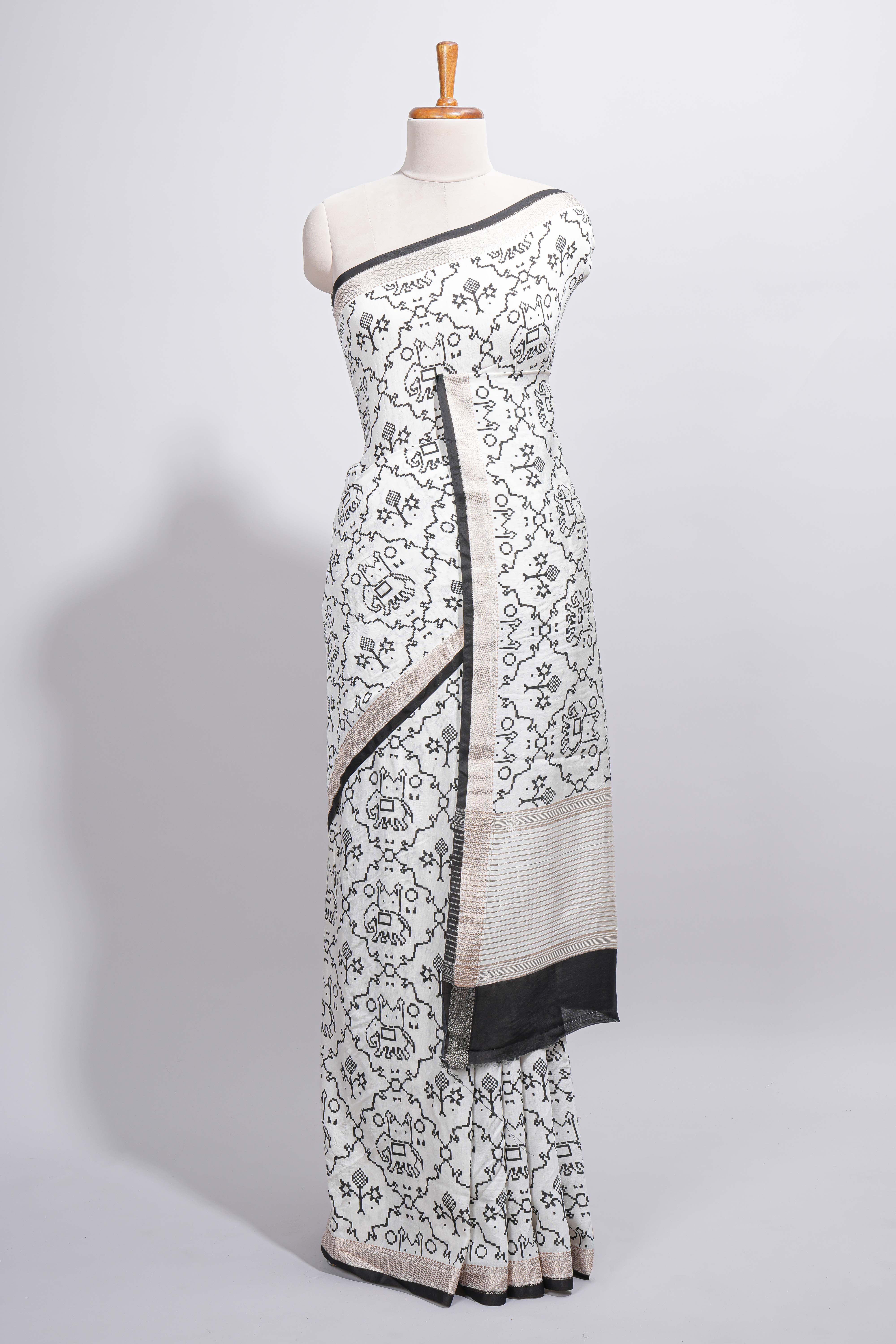 Elegant white Assam Silk saree traditional folk motif print floral patterns and a contrast black woven border The detailed pallu along with contrast blouse
