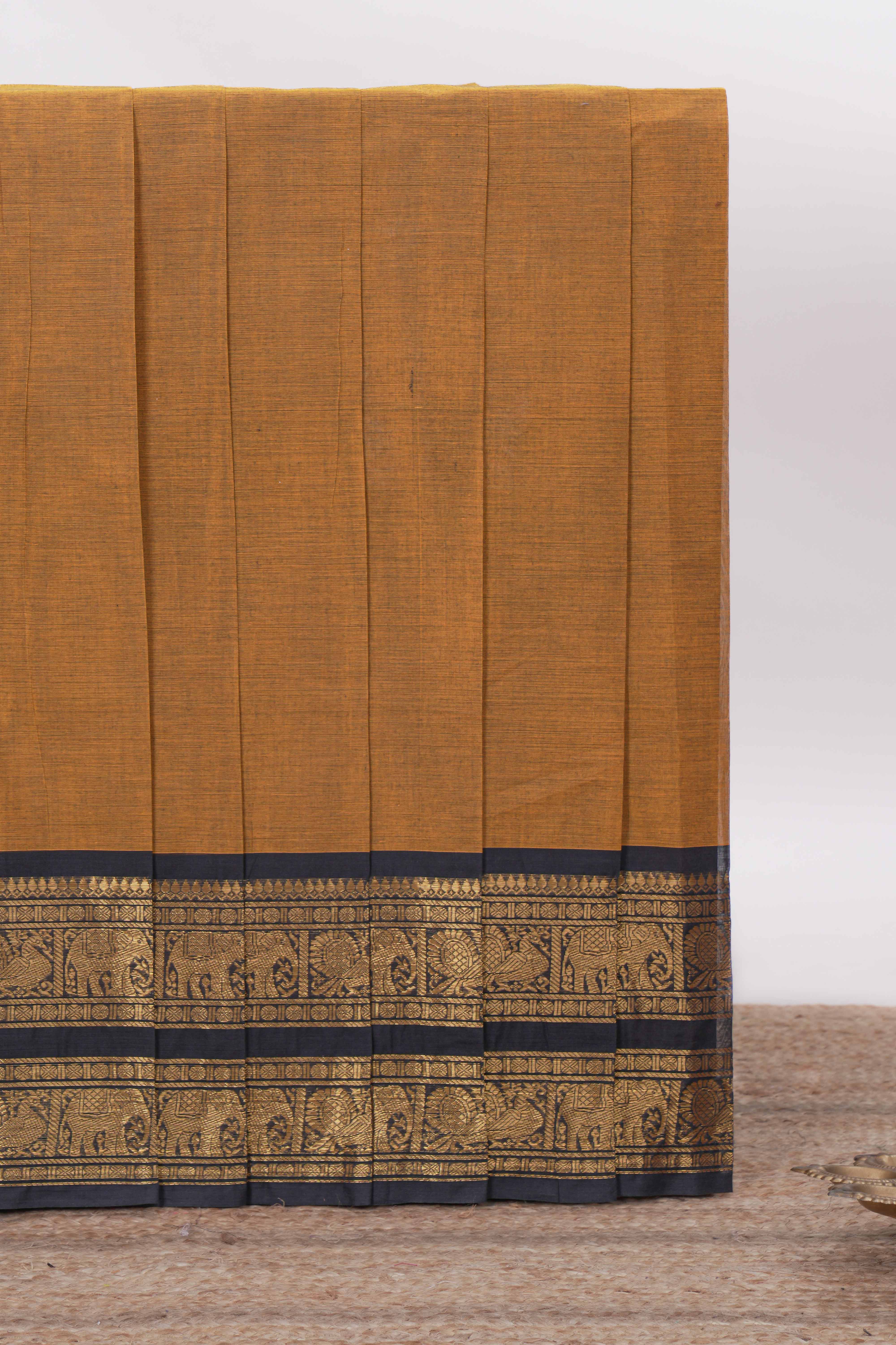 Deep Mustard yellow Chettinad cotton saree with a plain body antique gold zari elephant border along with matching blouse