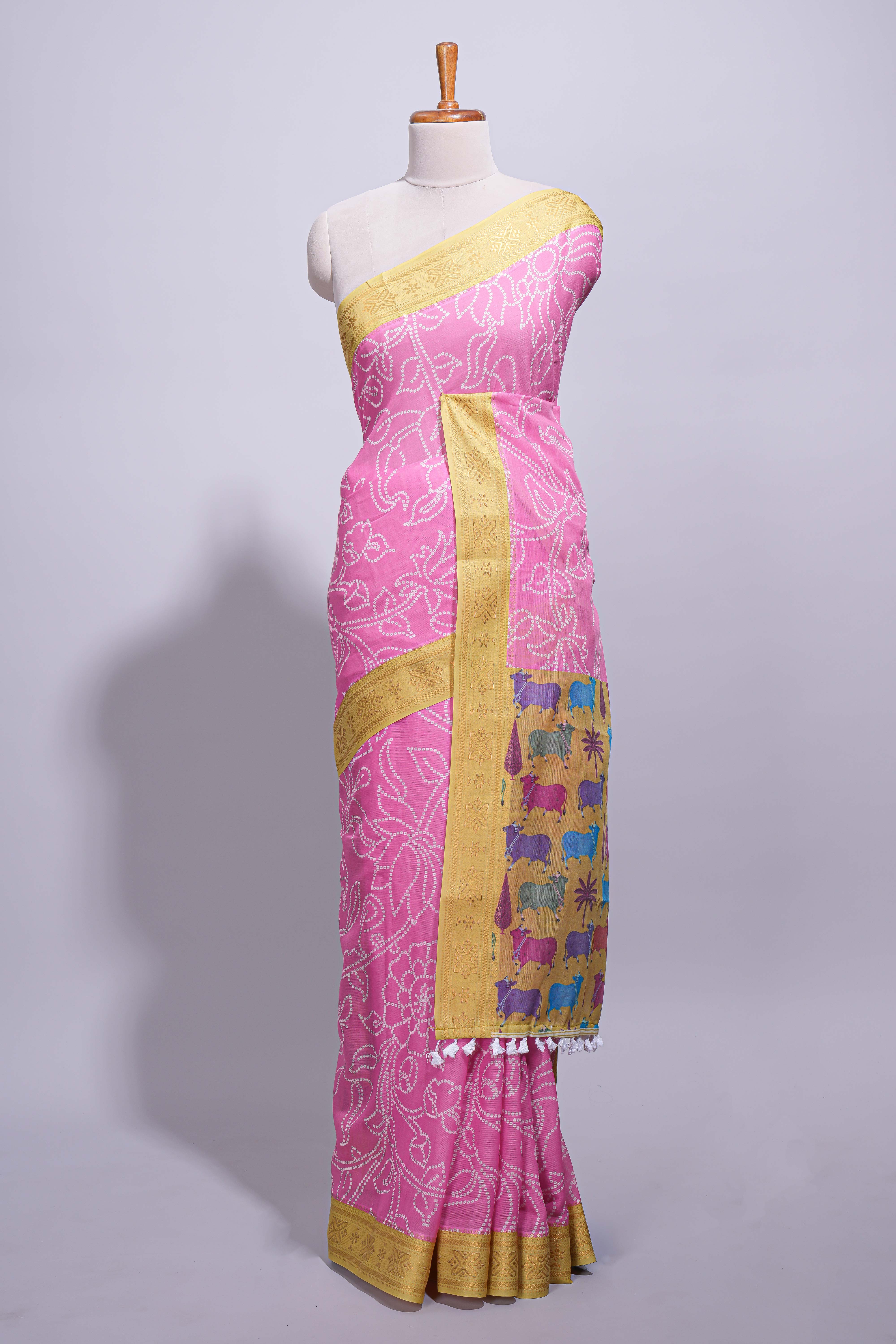 Pink linen saree with white dotted floral patterns with golden zari border and a multicolour pichwai motifs along with printed blouse