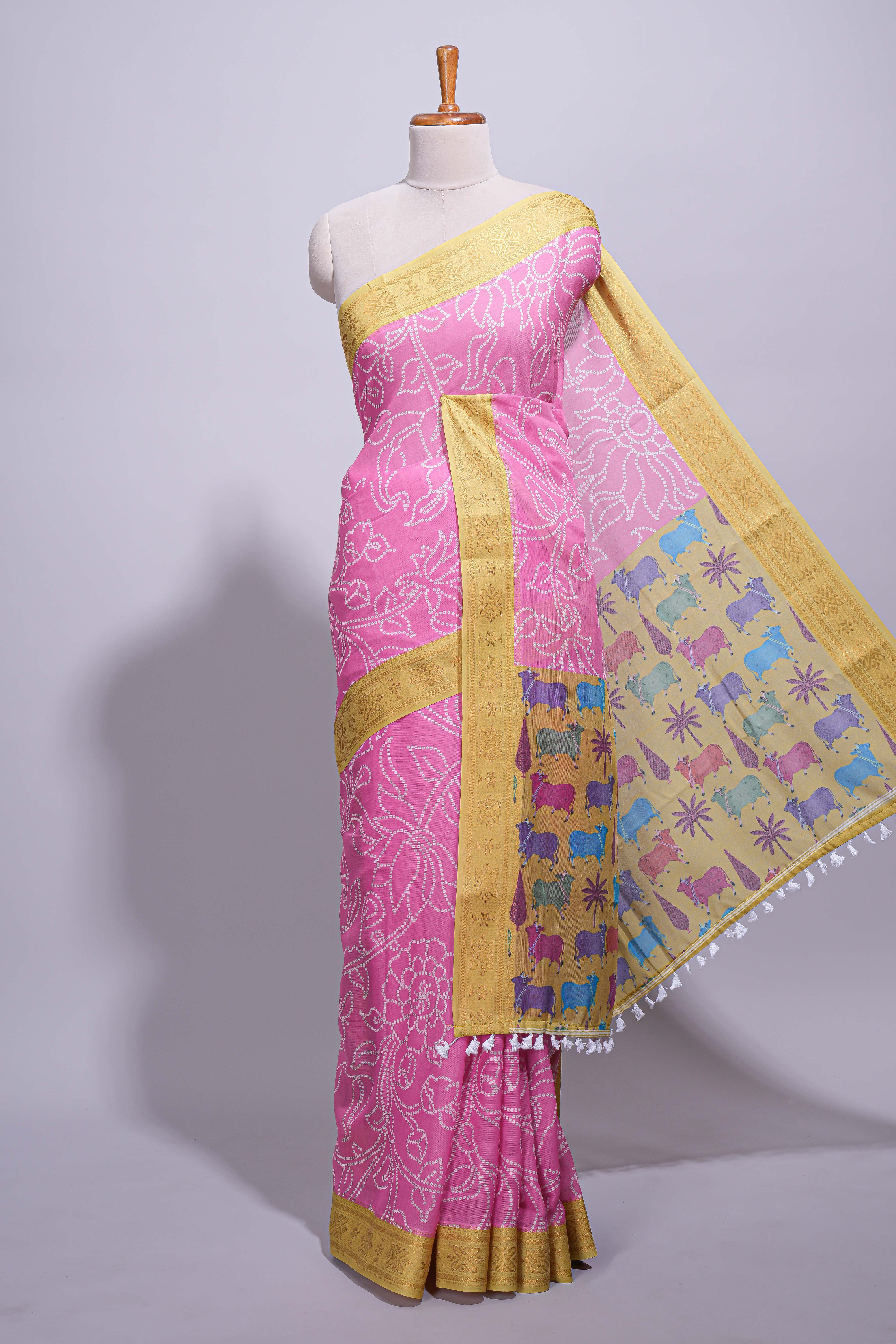 Pink linen saree with white dotted floral patterns with golden zari border and a multicolour pichwai motifs along with printed blouse