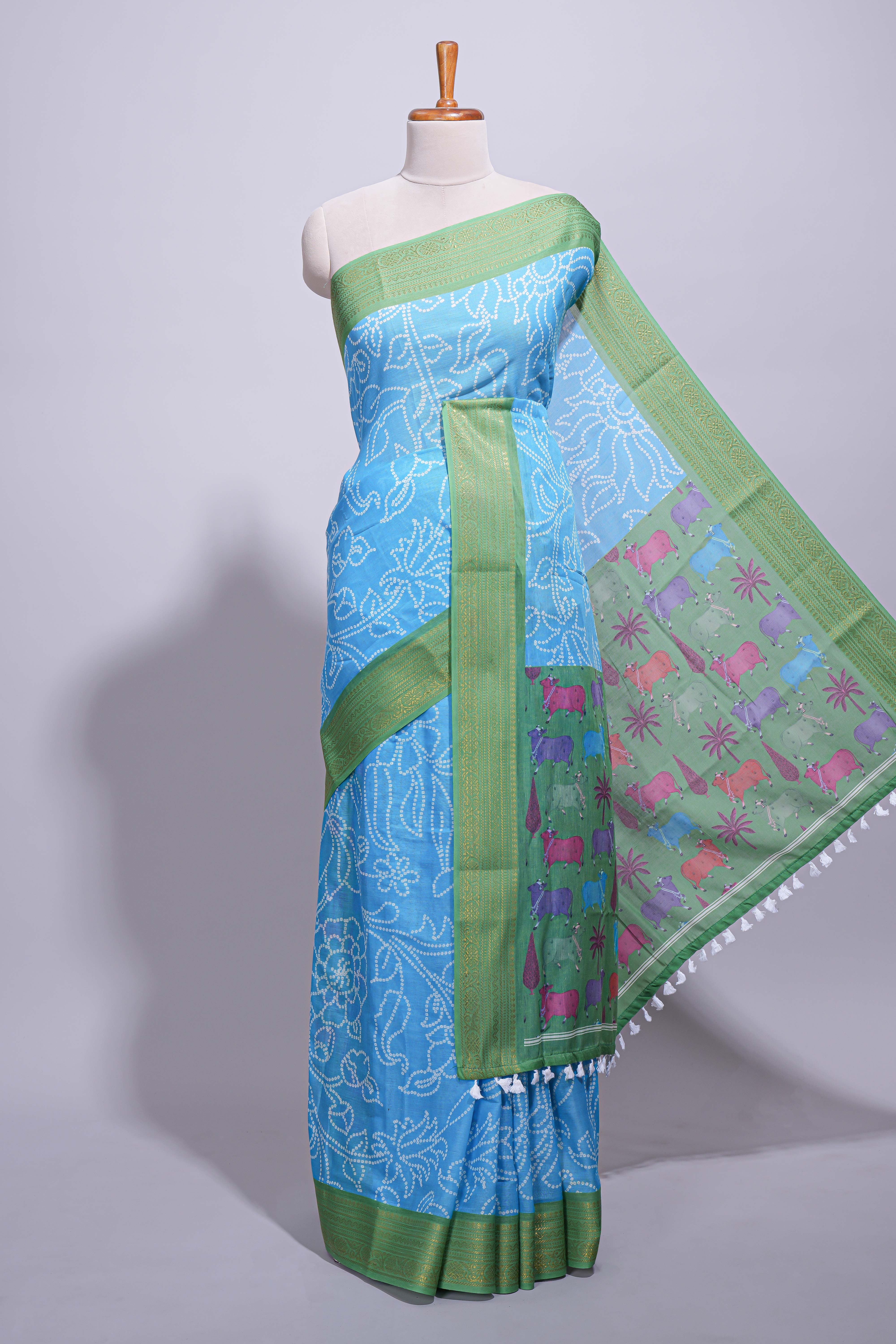 Blue linen saree with white dotted floral patterns with golden zari border and a multicolour pichwai motifs along with printed blouse
