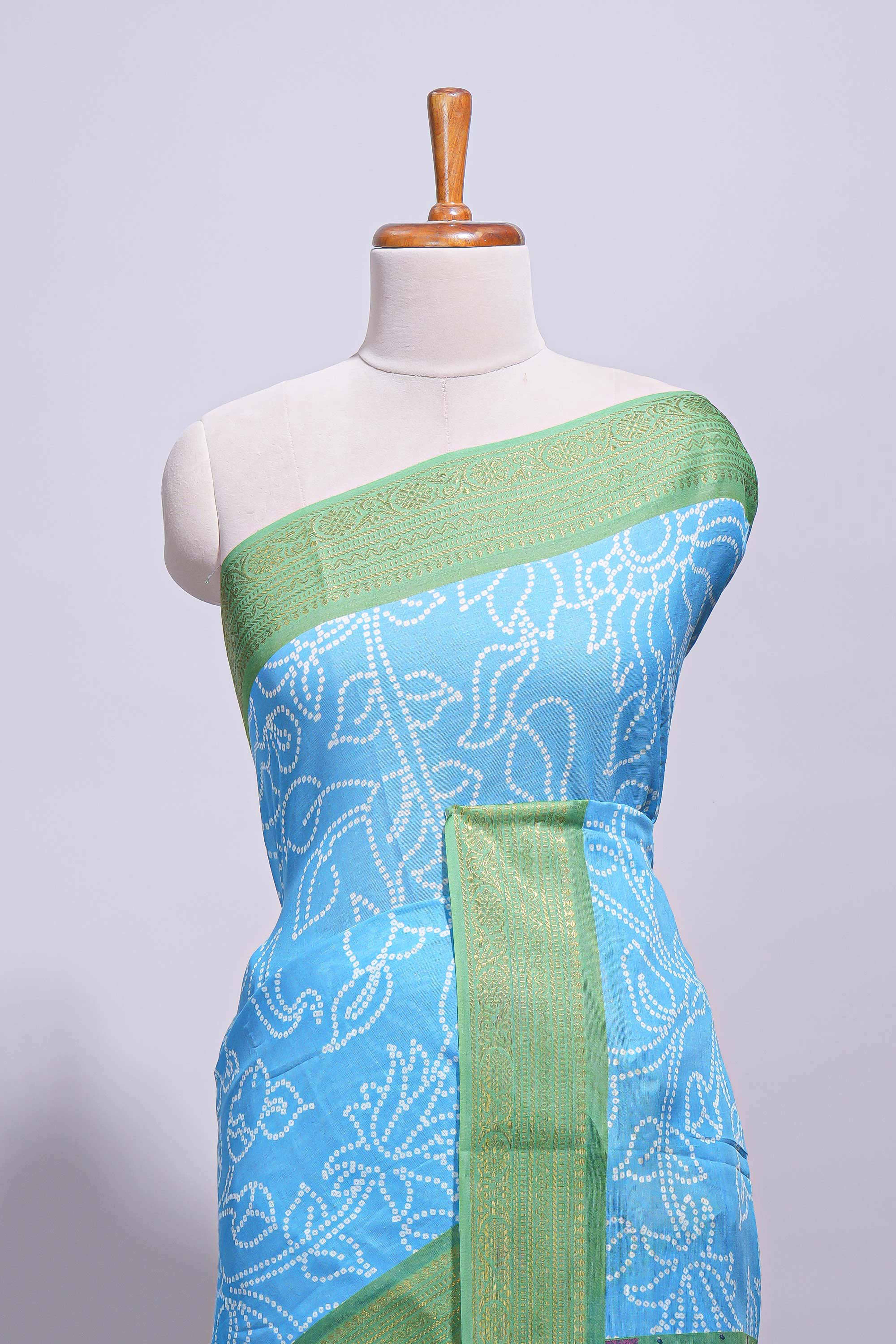 Blue linen saree with white dotted floral patterns with golden zari border and a multicolour pichwai motifs along with printed blouse