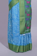 Blue linen saree with white dotted floral patterns with golden zari border and a multicolour pichwai motifs along with printed blouse