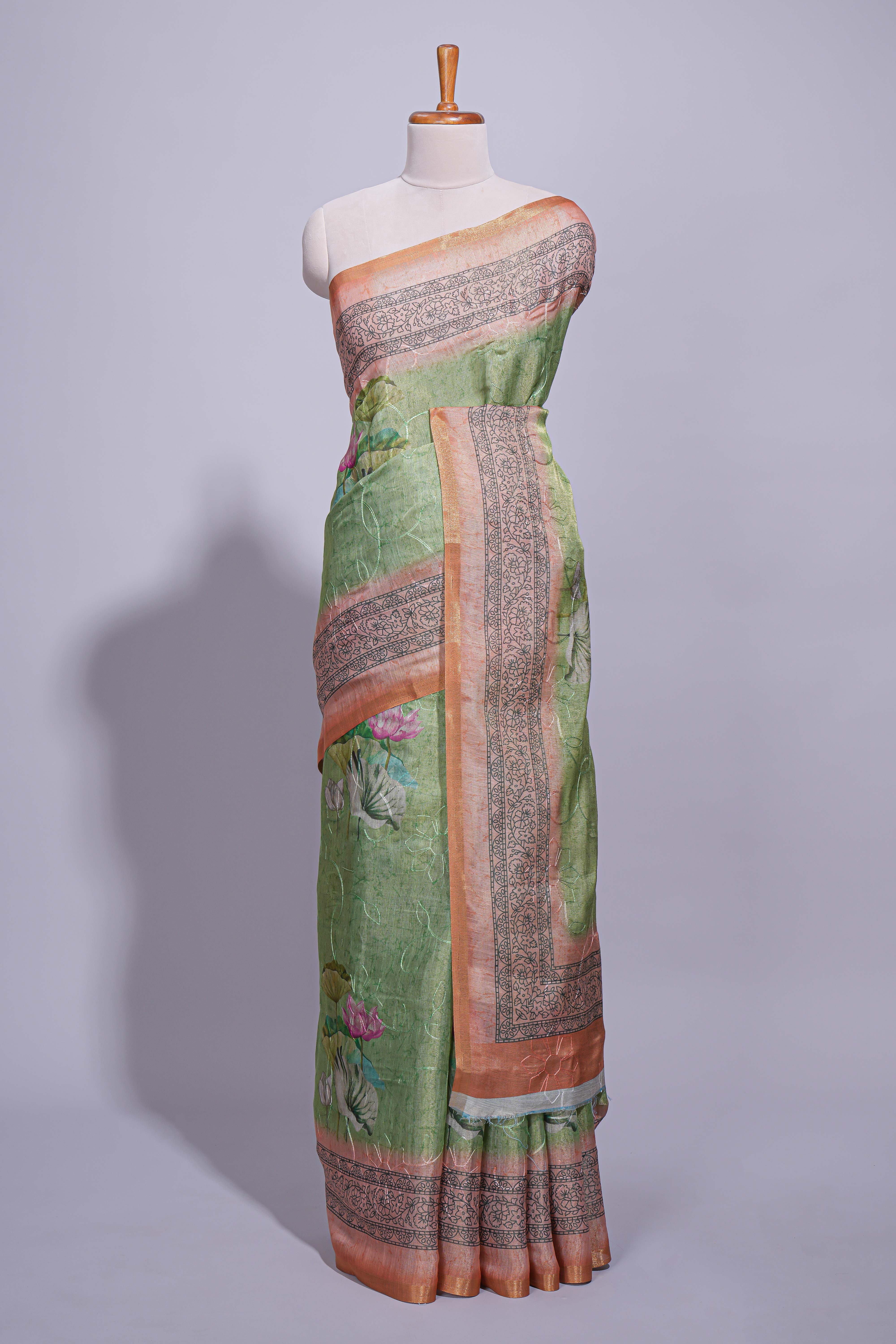 Soft green linen saree with floral print highlighted with afloral pallu and zari border along with contrast blouse piece