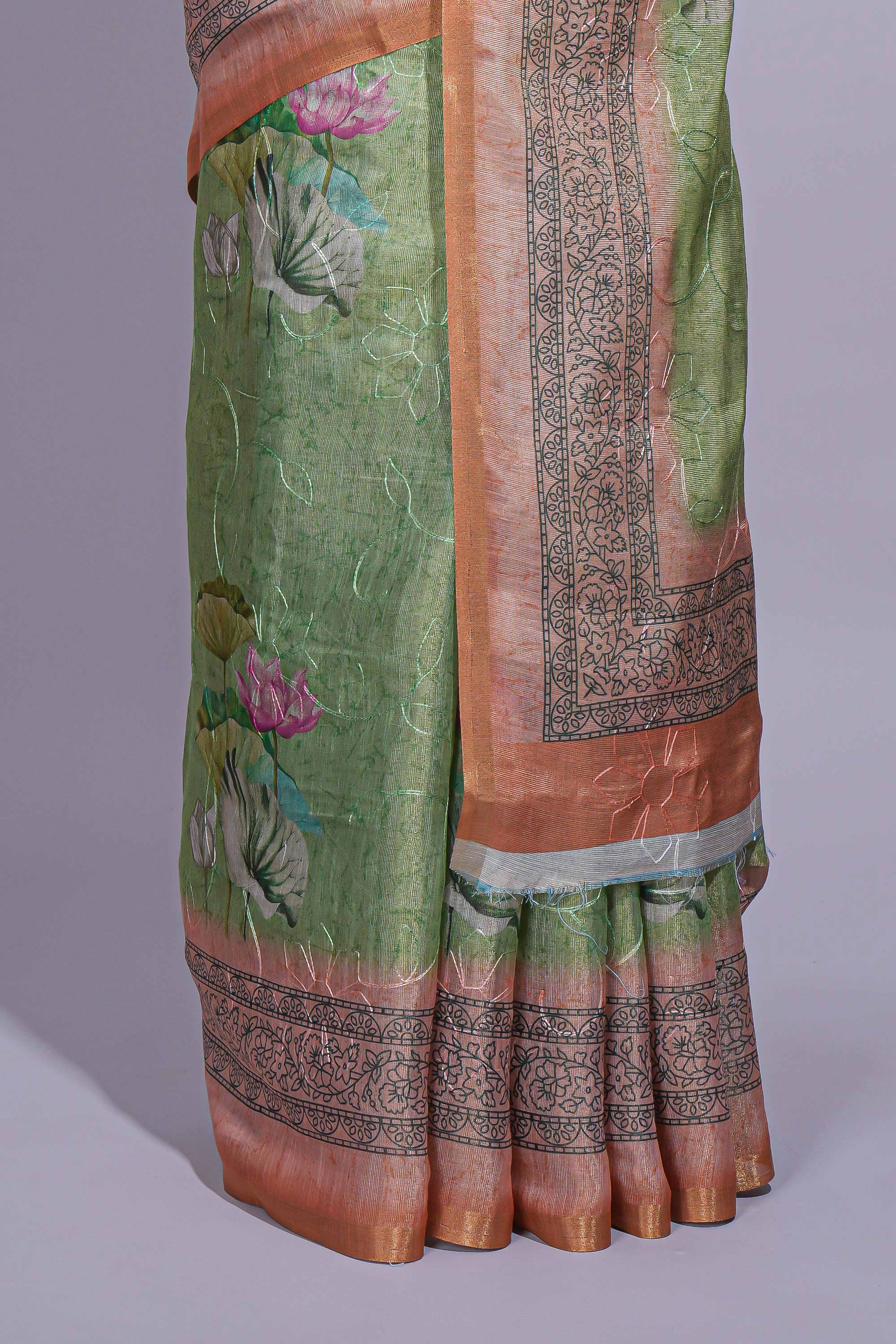 Soft green linen saree with floral print highlighted with afloral pallu and zari border along with contrast blouse piece