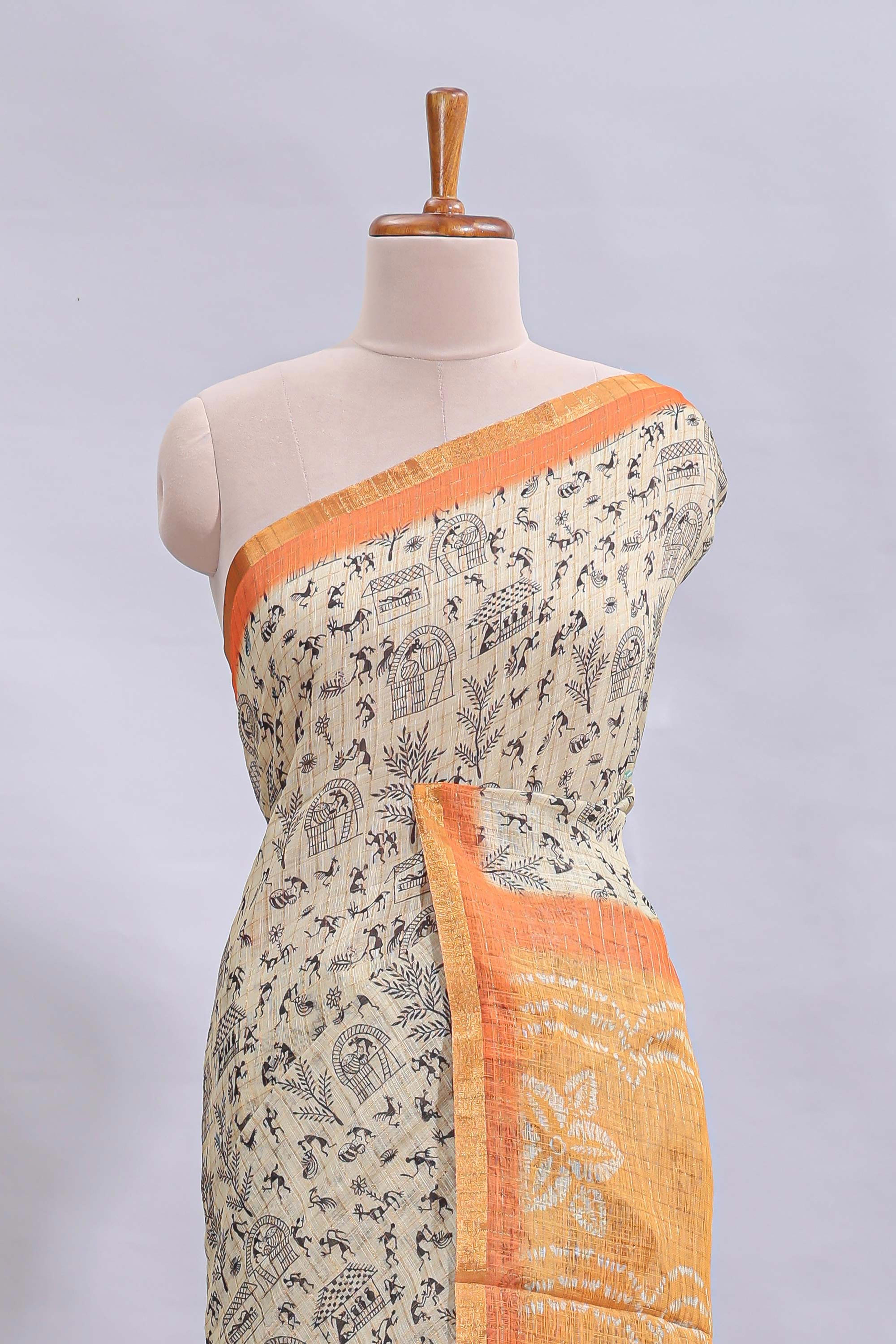 Beige tribal design warli print linen cotton saree with contrast orange zari border and floral design pallu