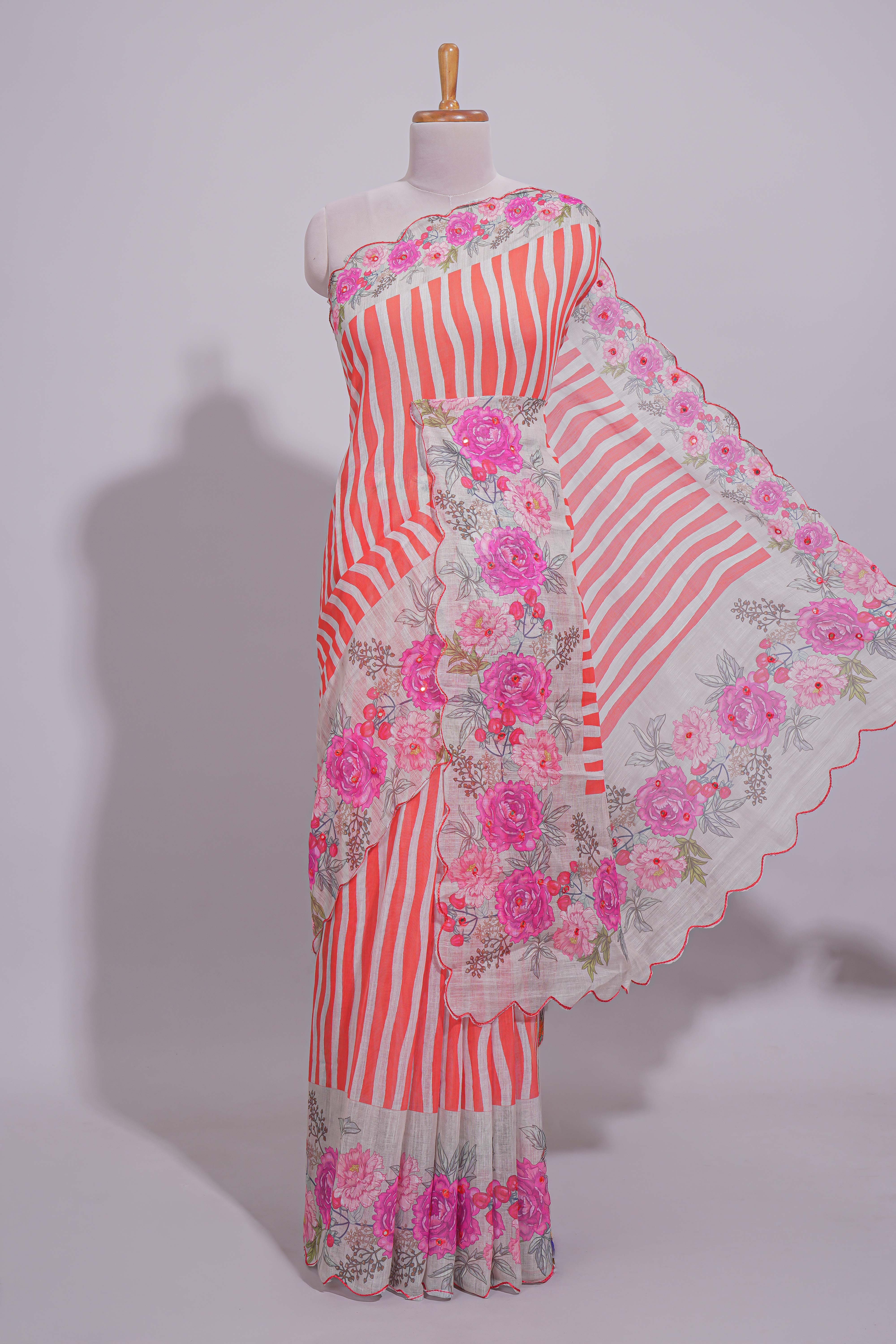 White Linen saree with orange stripes and vibrant pink floral scallop border with contrast printed blouse