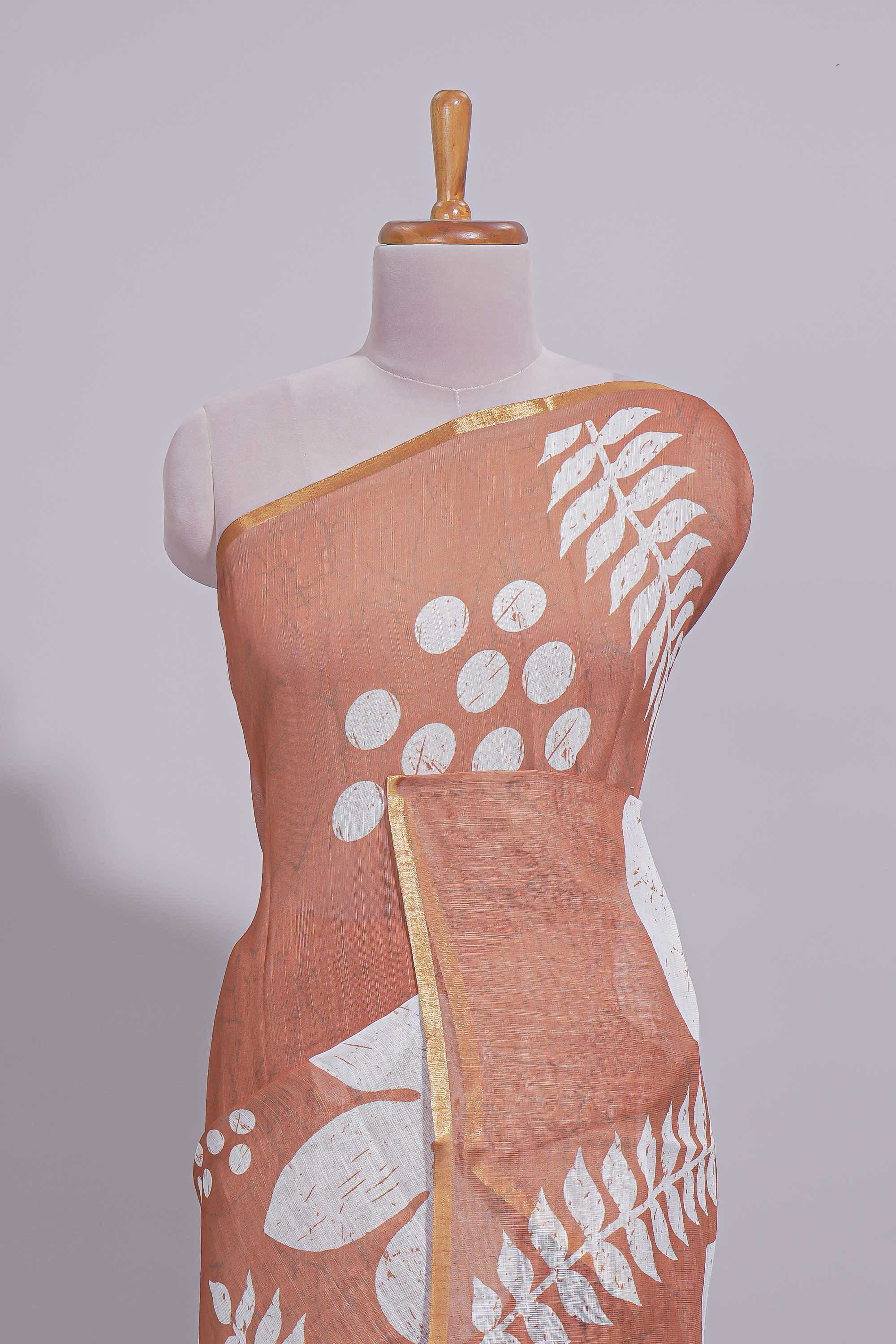 Brown linen saree with bold white floral and geometric prints finished with a subtle metallic border along with matching blouse