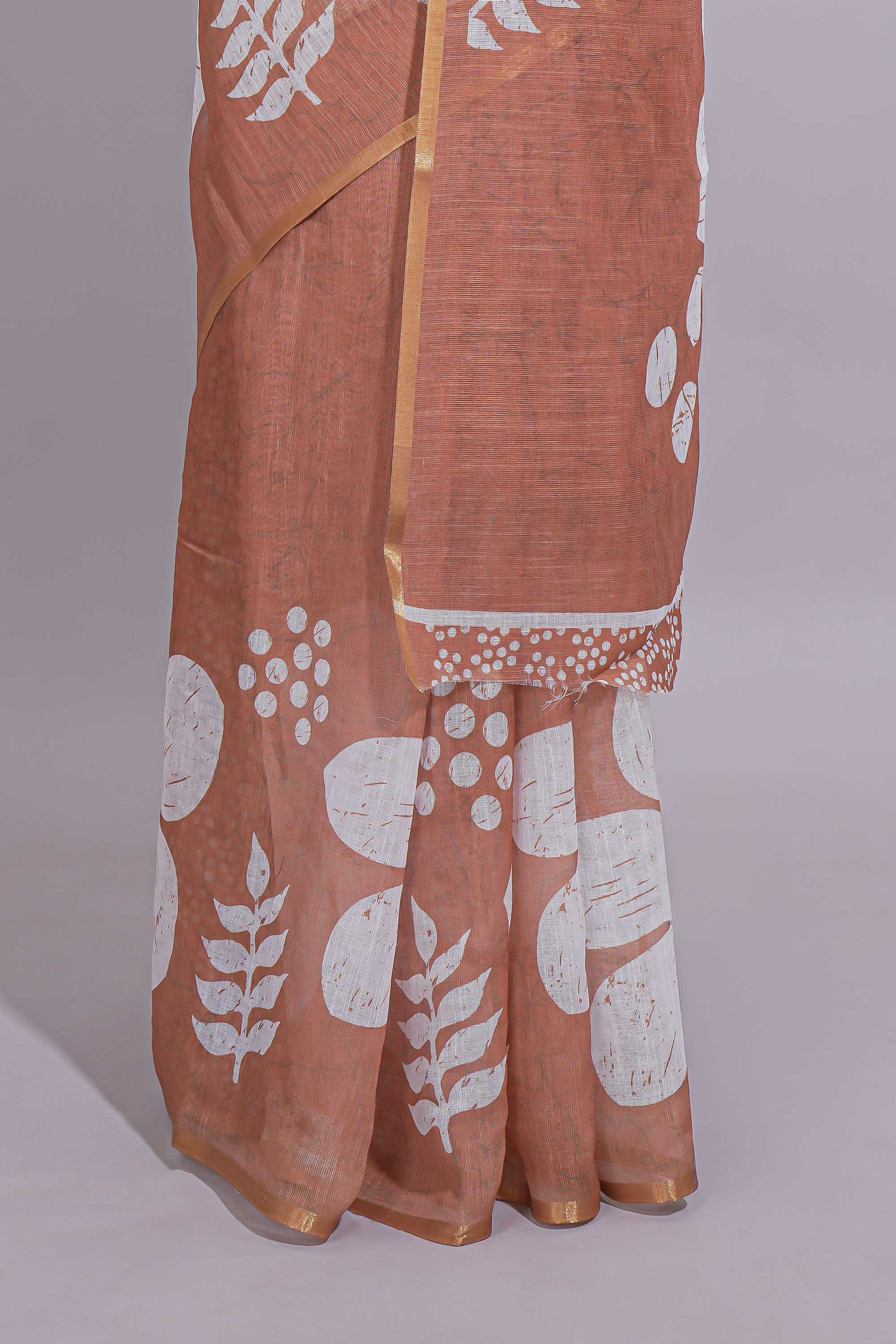 Brown linen saree with bold white floral and geometric prints finished with a subtle metallic border along with matching blouse