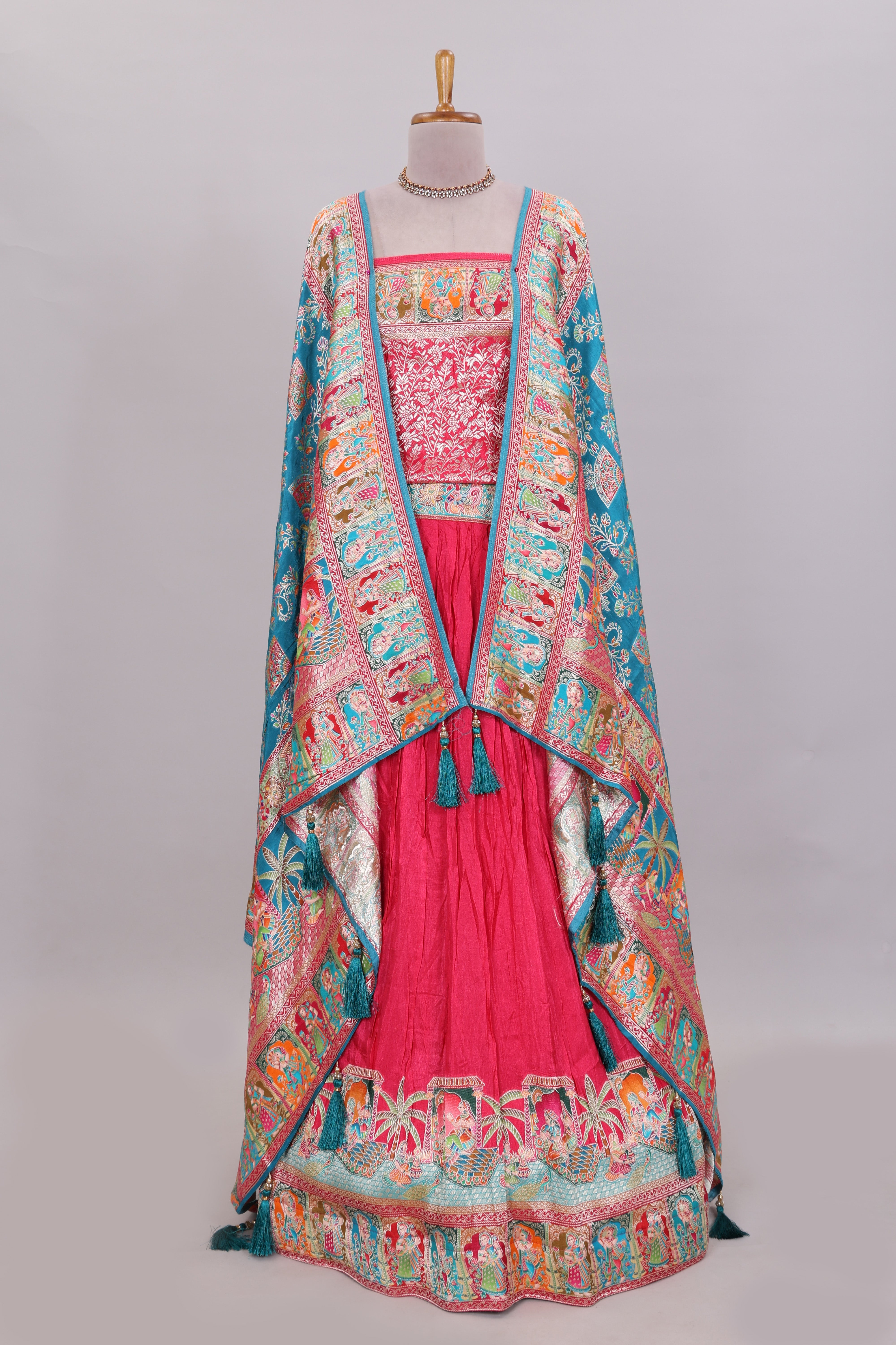 Rani pink plain lehenga featuring with human figure motifs with floral and ornamental detailing border Paired with a teal blue floral designedshawl