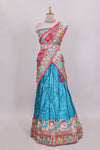 Blue plain lehenga featuring with human figure motifs with floral and ornamental detailing border Paired with a pink floral designedshawl