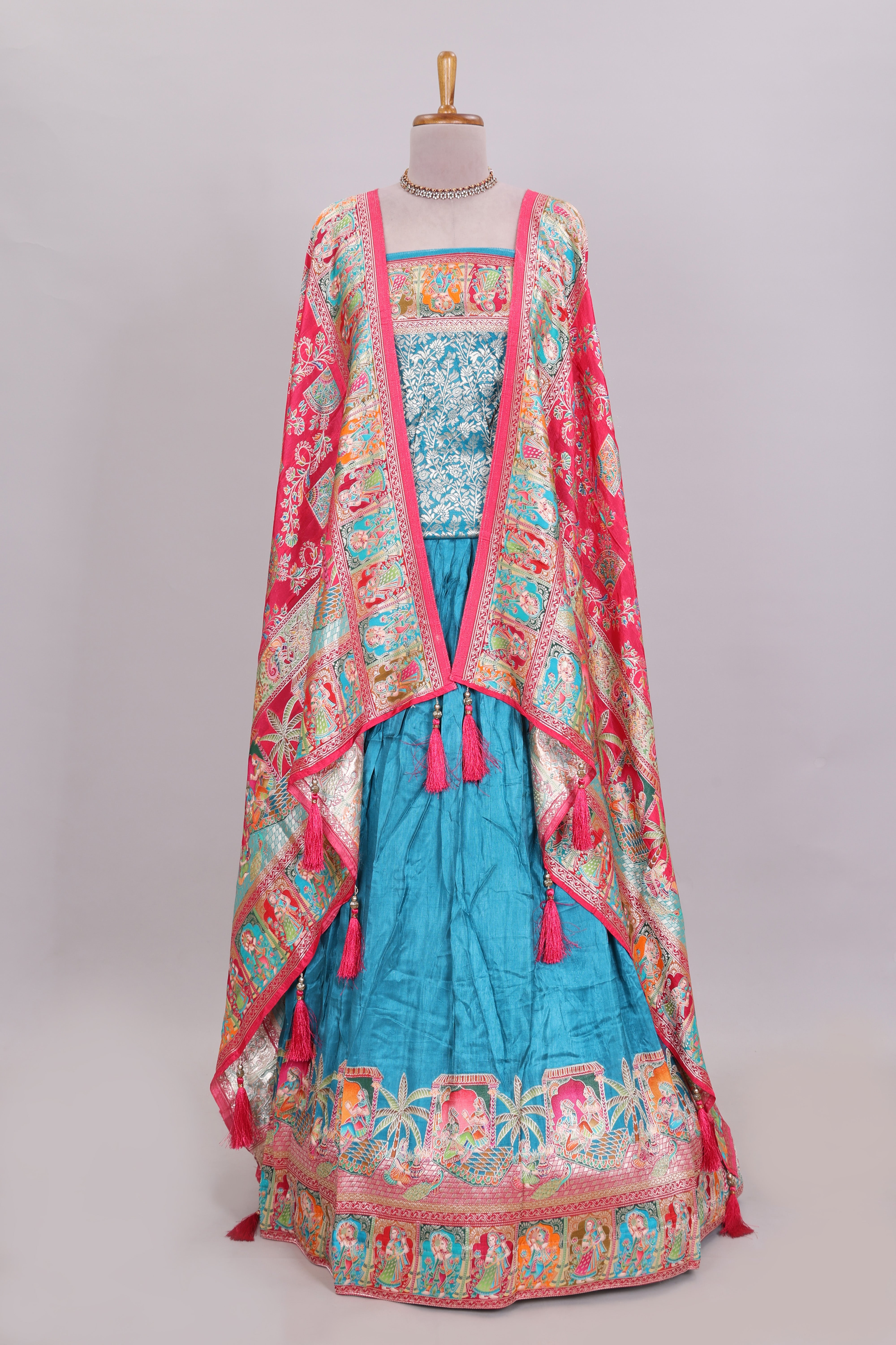 Blue plain lehenga featuring with human figure motifs with floral and ornamental detailing border Paired with a pink floral designedshawl