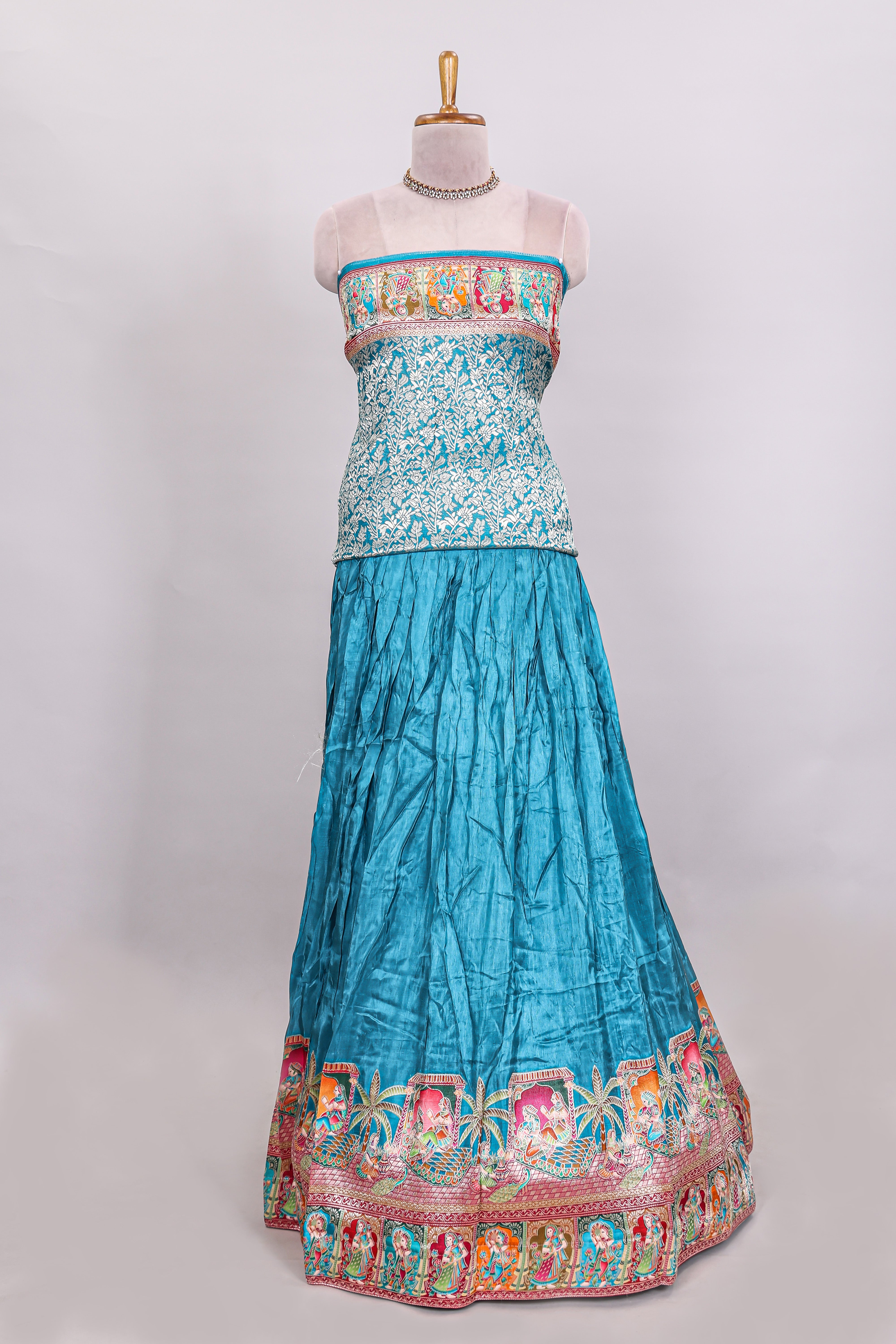 Blue plain lehenga featuring with human figure motifs with floral and ornamental detailing border Paired with a pink floral designedshawl
