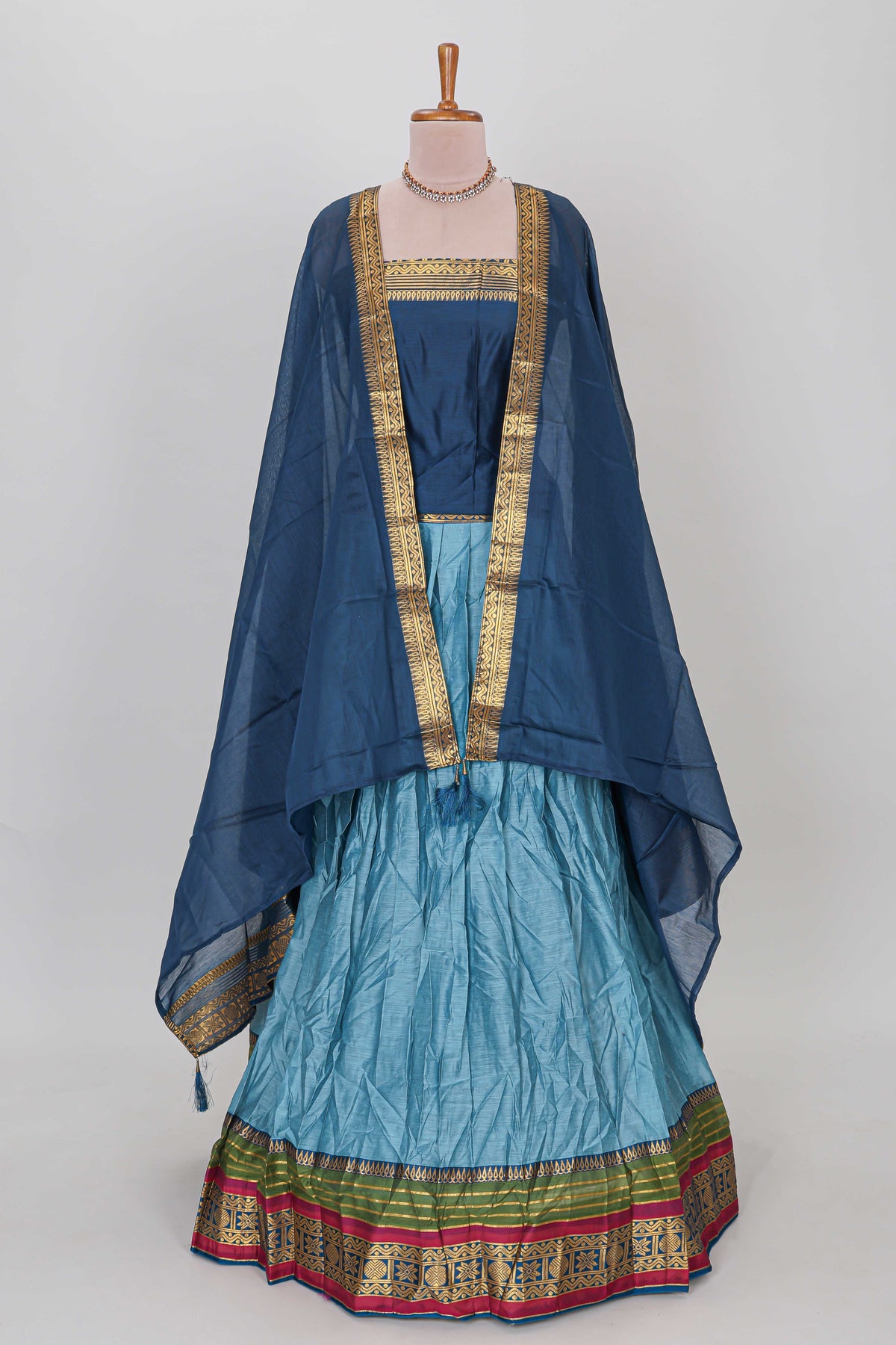 Light blue shade plain lehanga featuring contrasting zari border and blouse paired with dark blue shawl