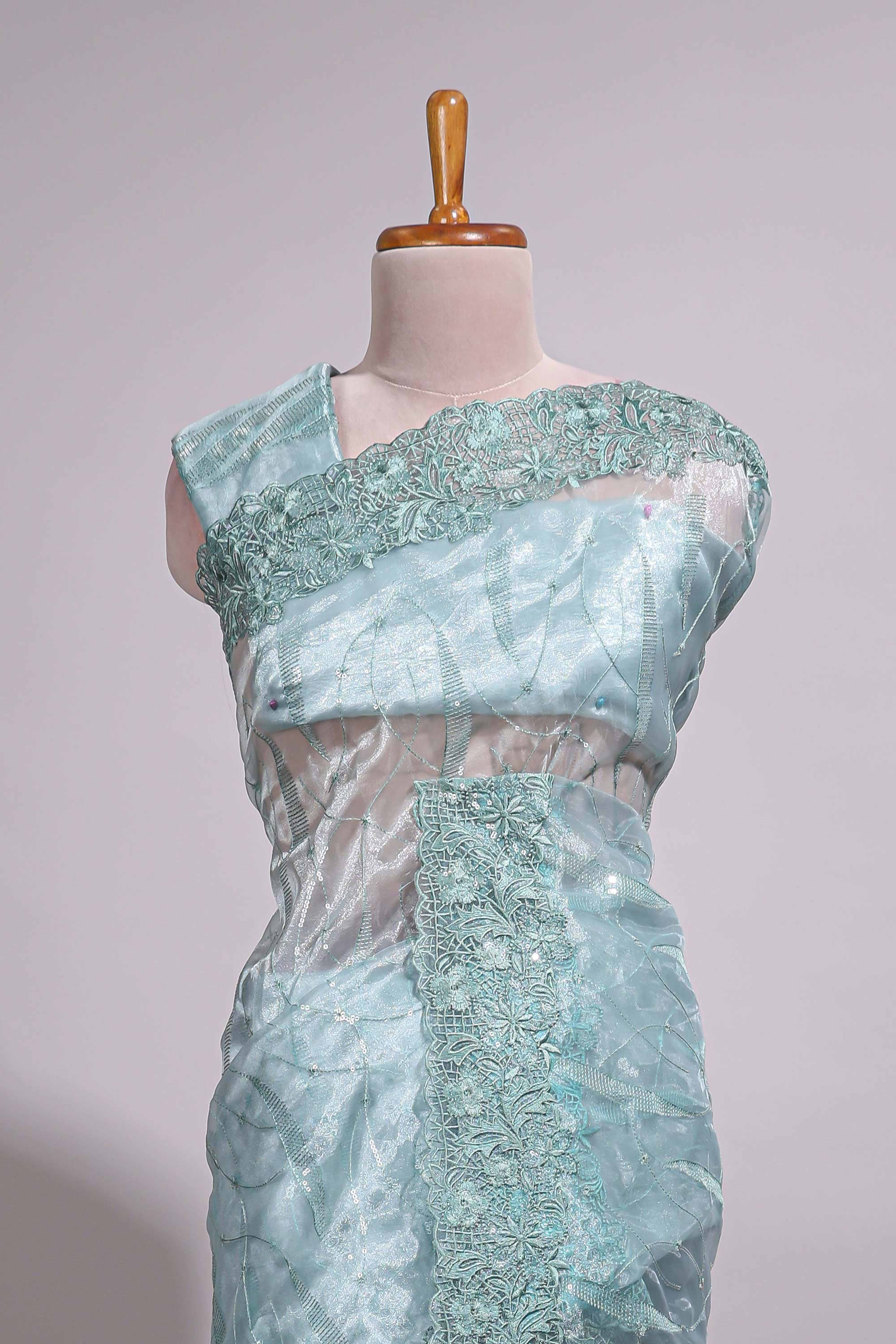 Pastel blue organza saree featuring delicate floral embroidery, intricate lace detailing on the border and pallu with a scalloped finishing along with matching blouse