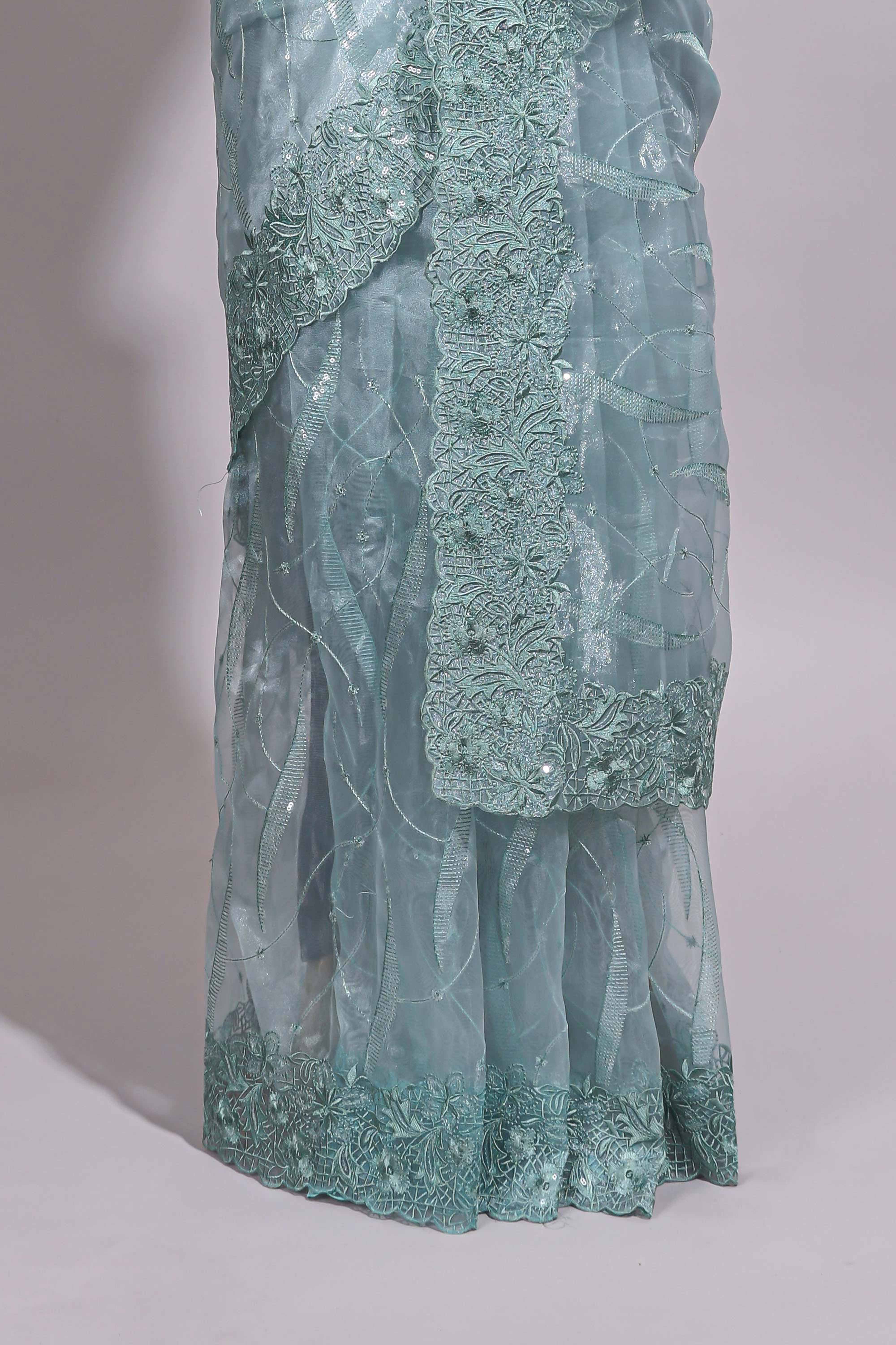 Pastel blue organza saree featuring delicate floral embroidery, intricate lace detailing on the border and pallu with a scalloped finishing along with matching blouse