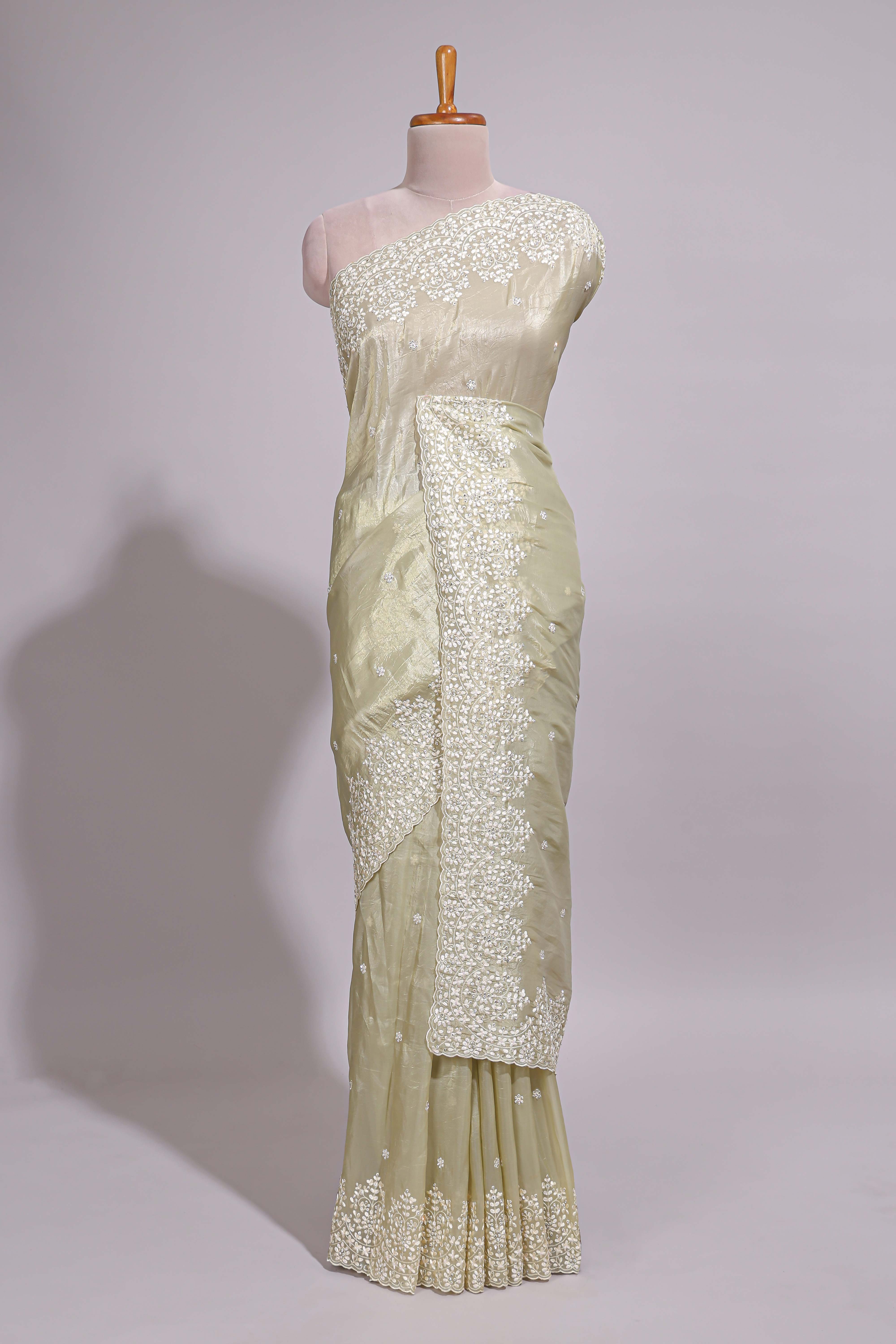 Pastel ivory organza saree with delicate floral embroidery intricate lace border and scalloped pallu detailing