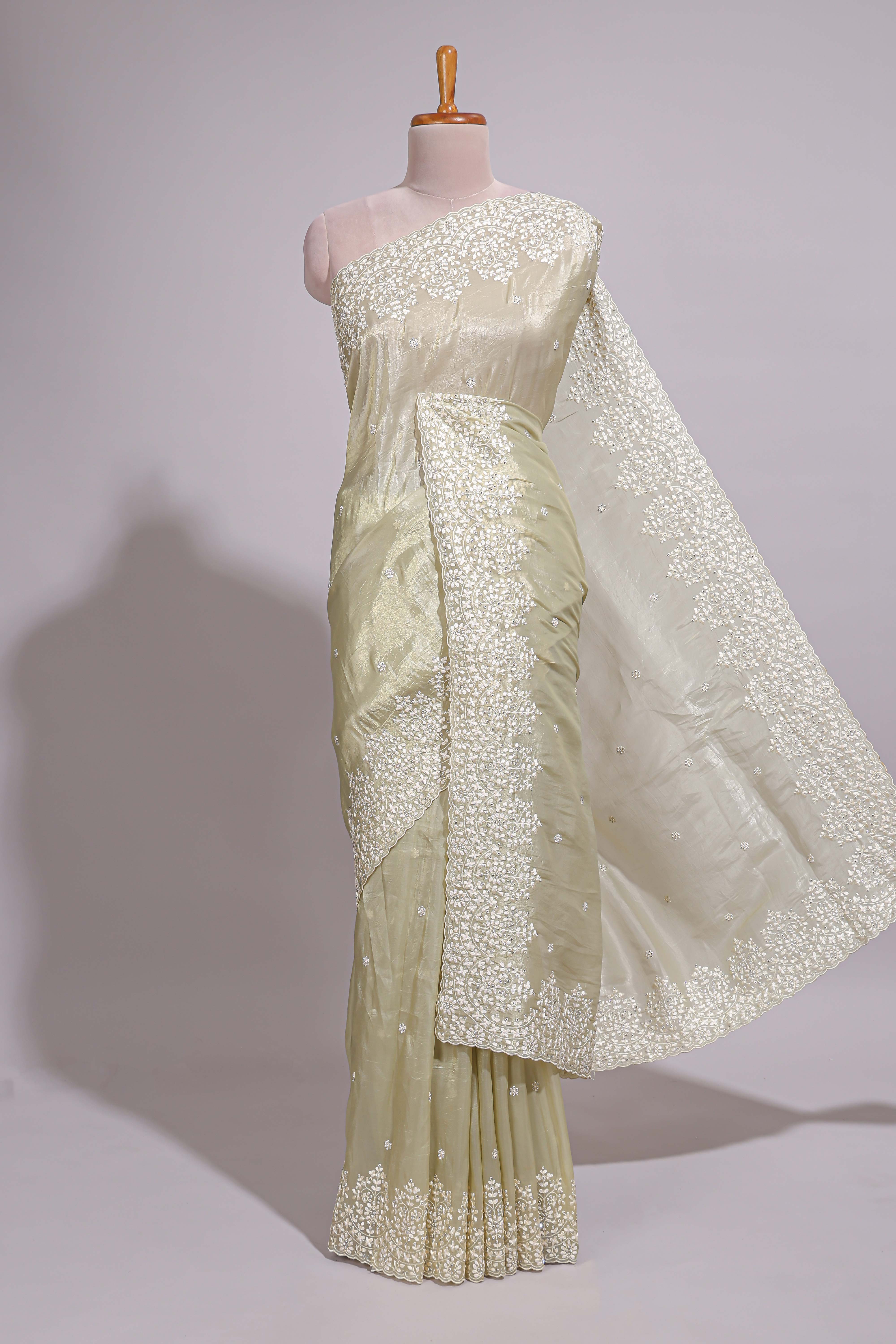 Pastel ivory organza saree with delicate floral embroidery intricate lace border and scalloped pallu detailing
