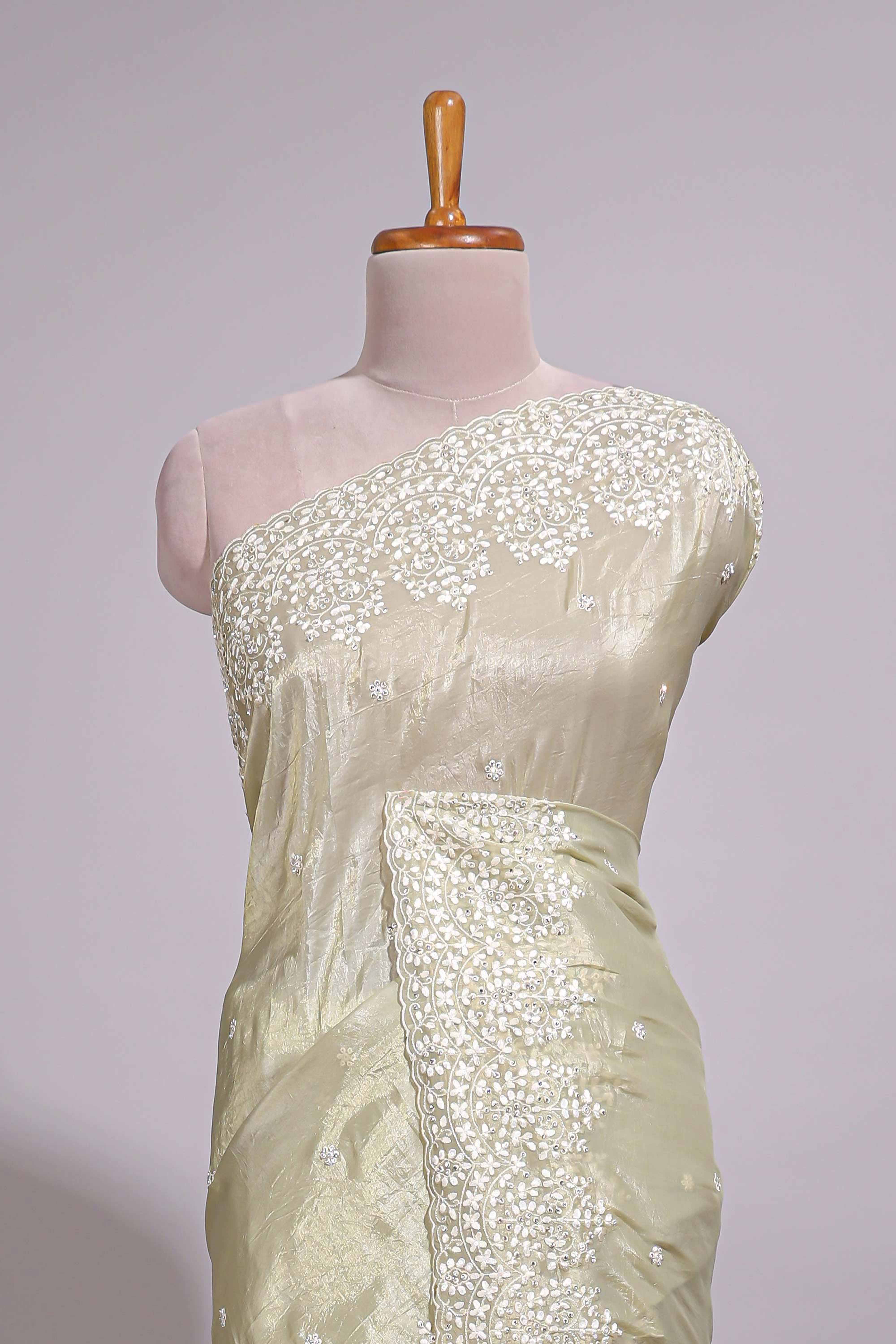 Pastel ivory organza saree with delicate floral embroidery intricate lace border and scalloped pallu detailing