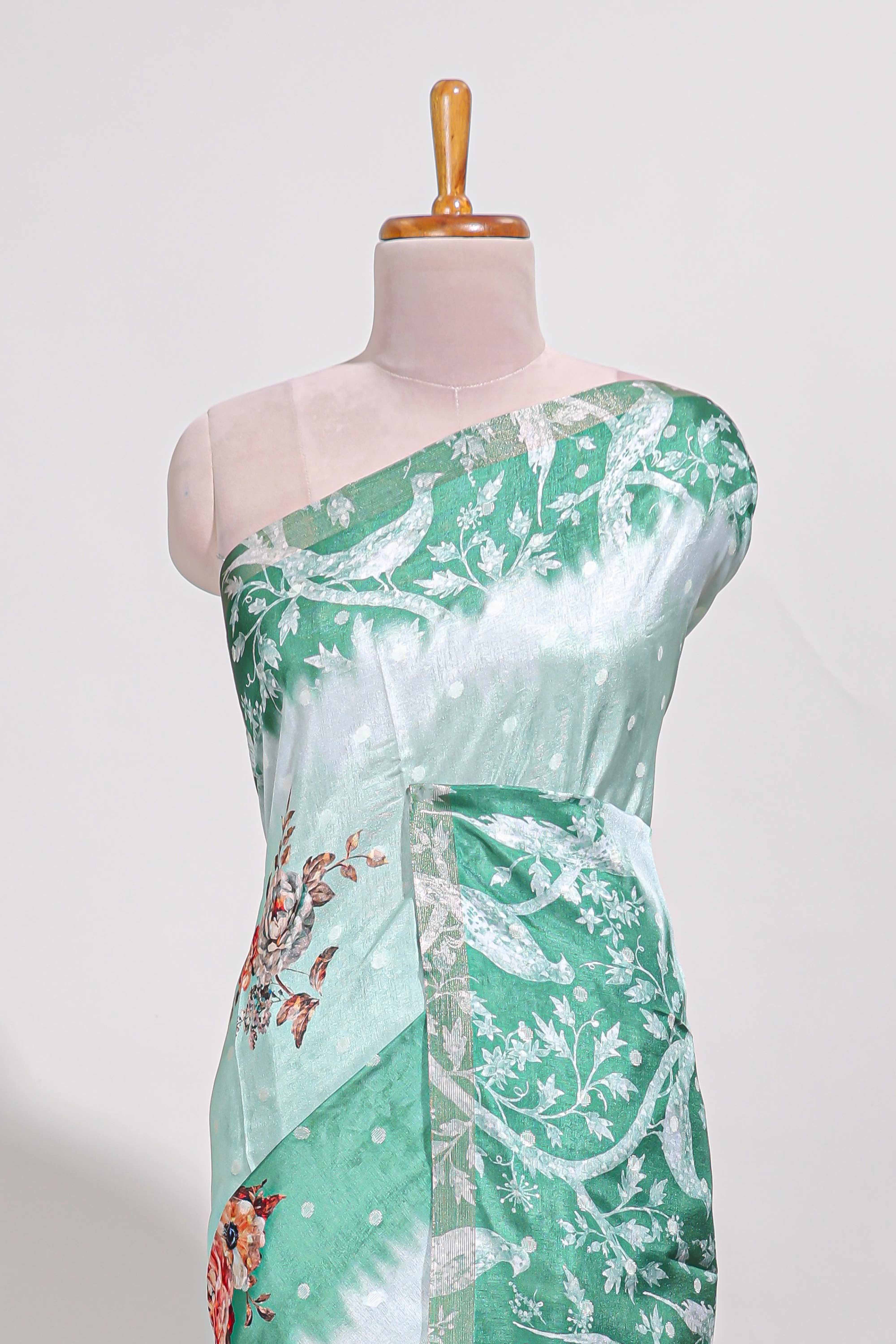 Green Tussar saree with a floral body featuring bird motifs a printed pallu with tassels and a matchingfloral blouse piece
