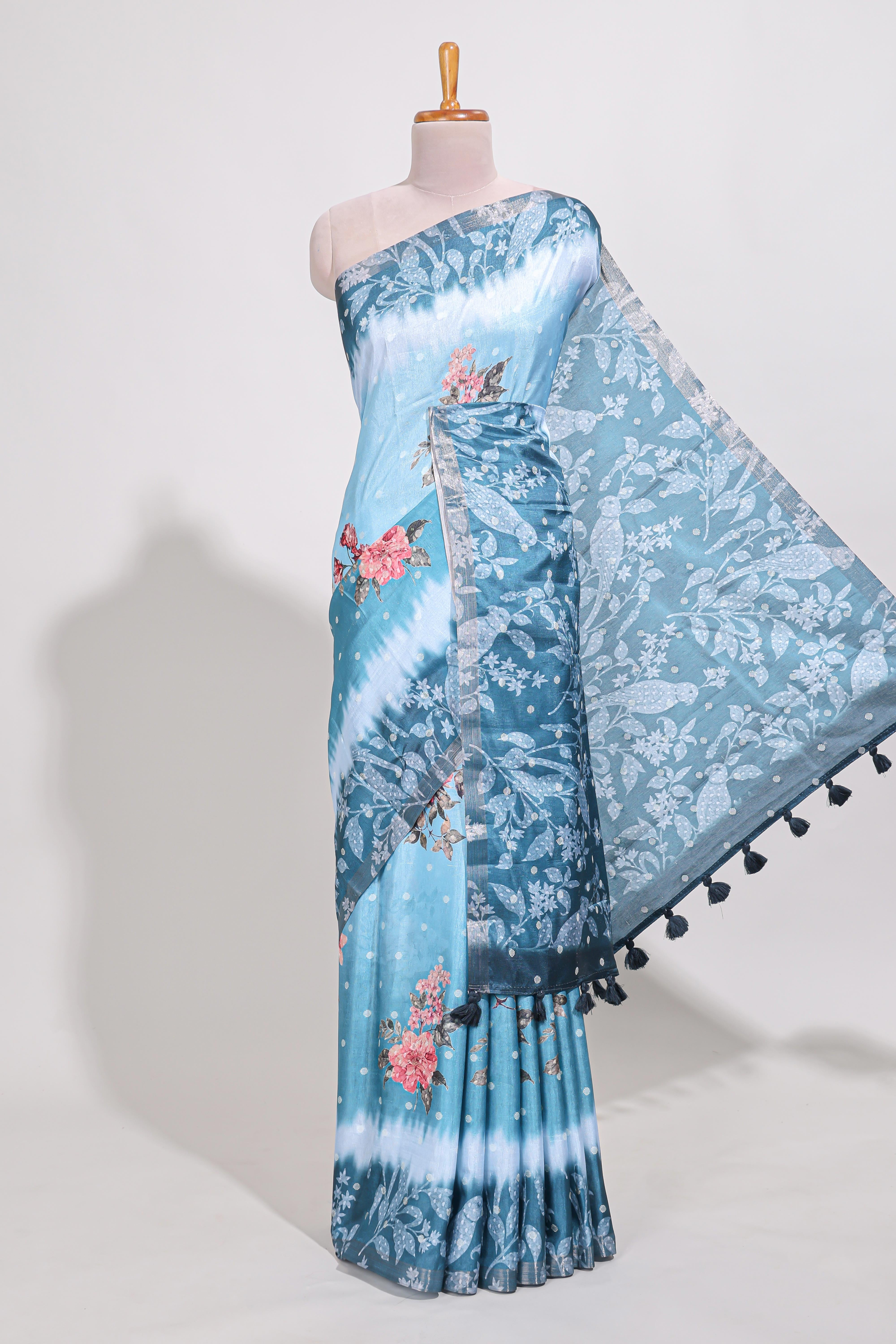 Blue Tussar saree with a floral body featuring bird motifs a printed pallu with tassels and a matchingfloral blouse piece