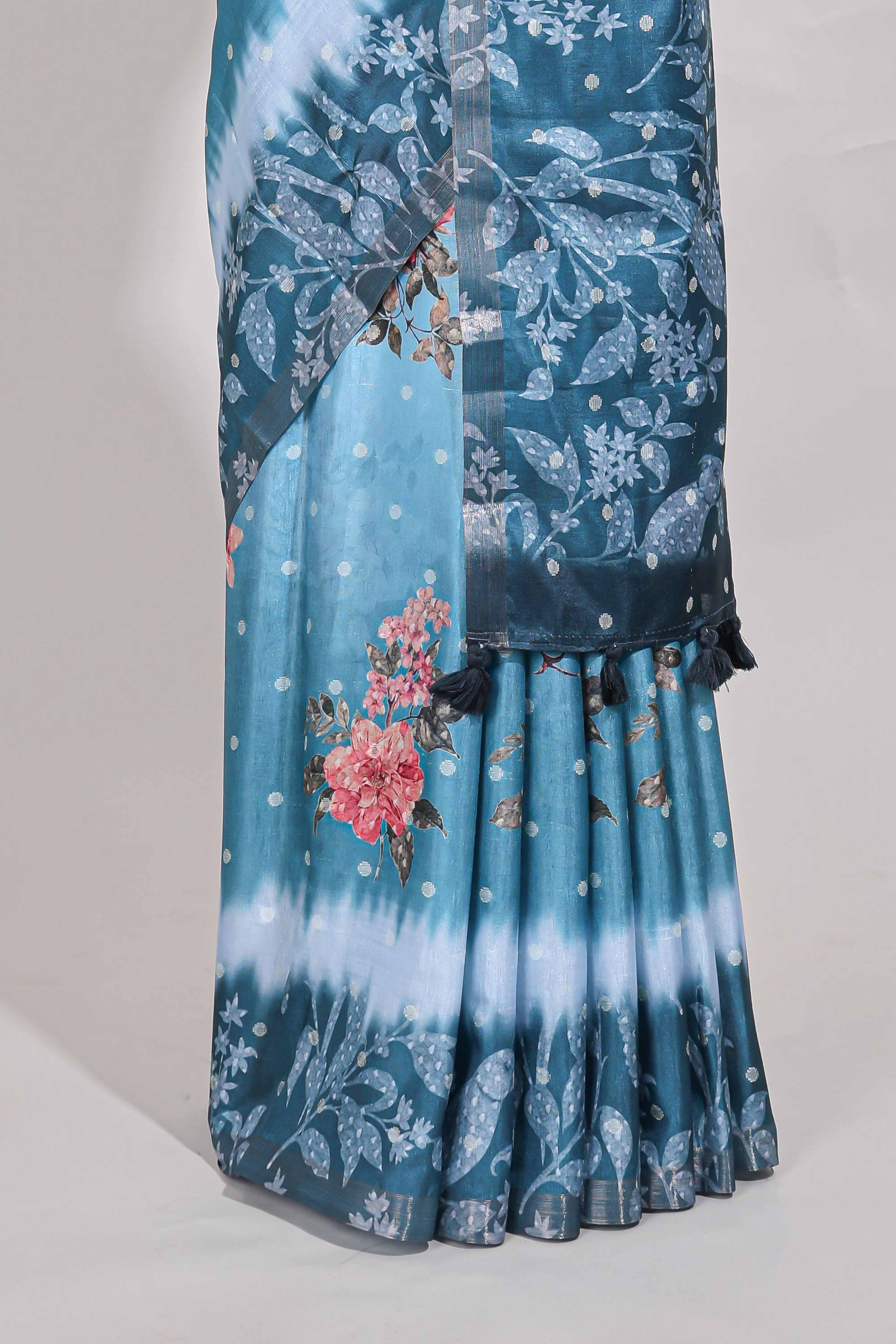 Blue Tussar saree with a floral body featuring bird motifs a printed pallu with tassels and a matchingfloral blouse piece