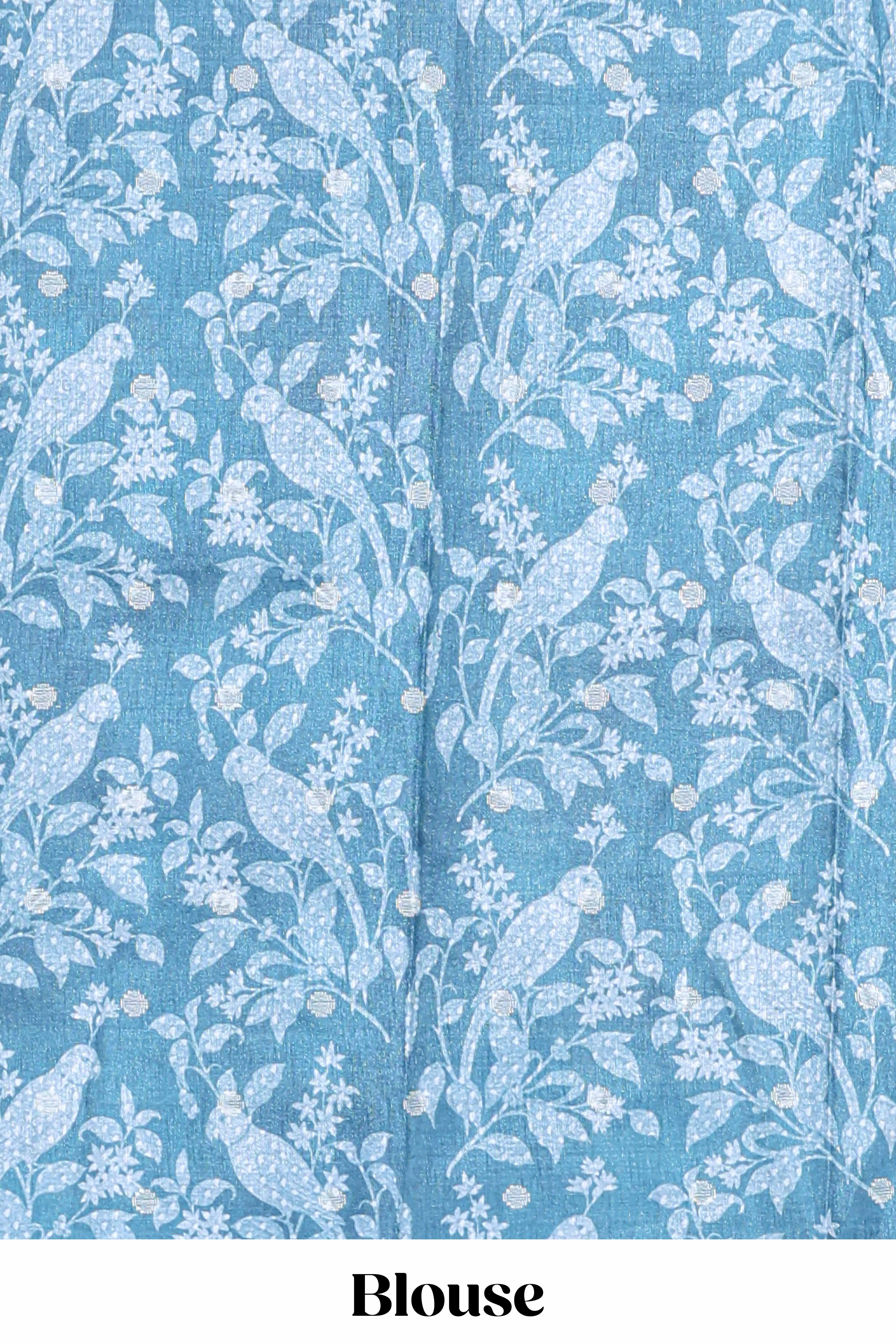 Blue Tussar saree with a floral body featuring bird motifs a printed pallu with tassels and a matchingfloral blouse piece