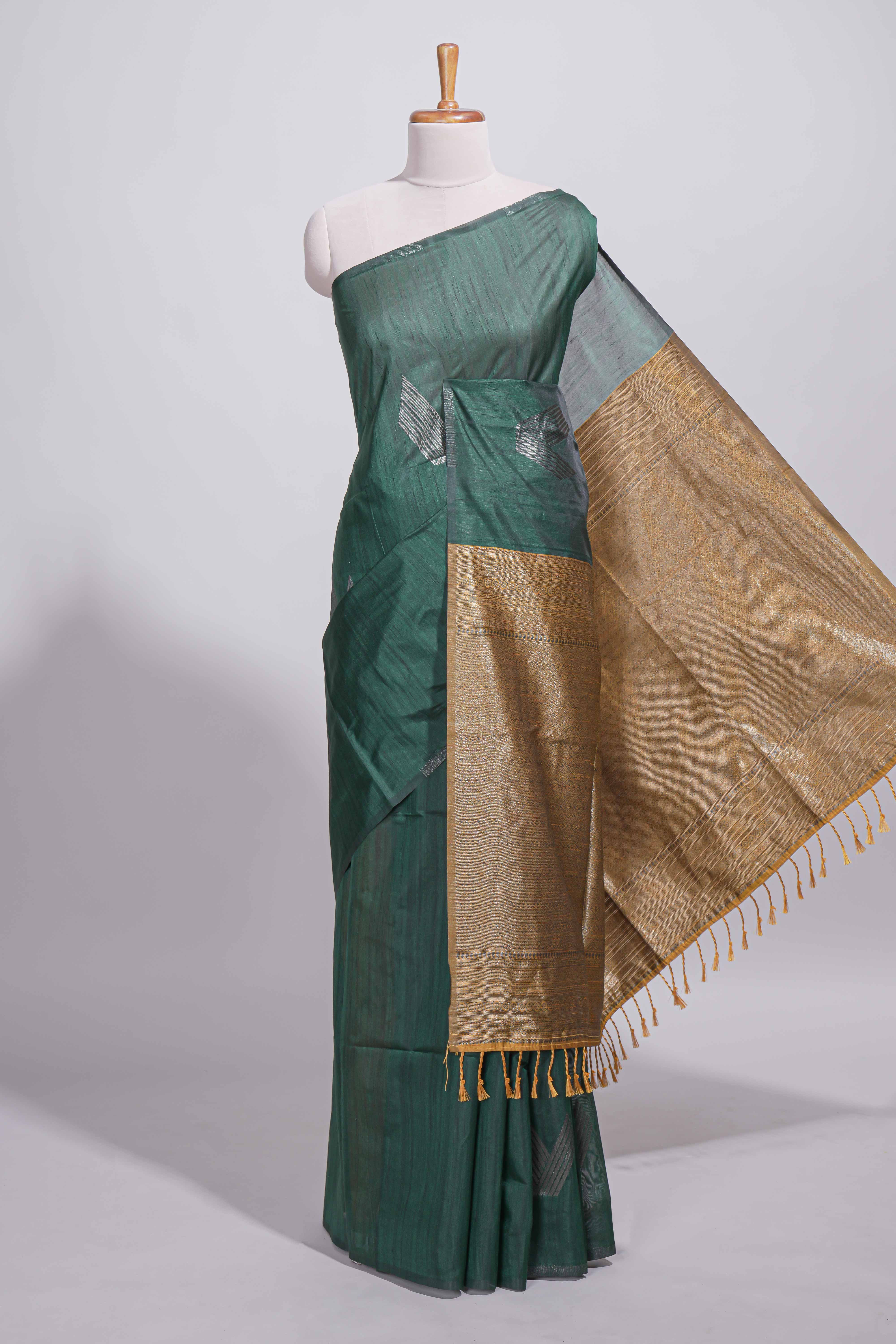 Bottle green tussar saree with subtle silver woven motifs paired with a rich antique gold zari pallu with tassels with contrast blouse piece