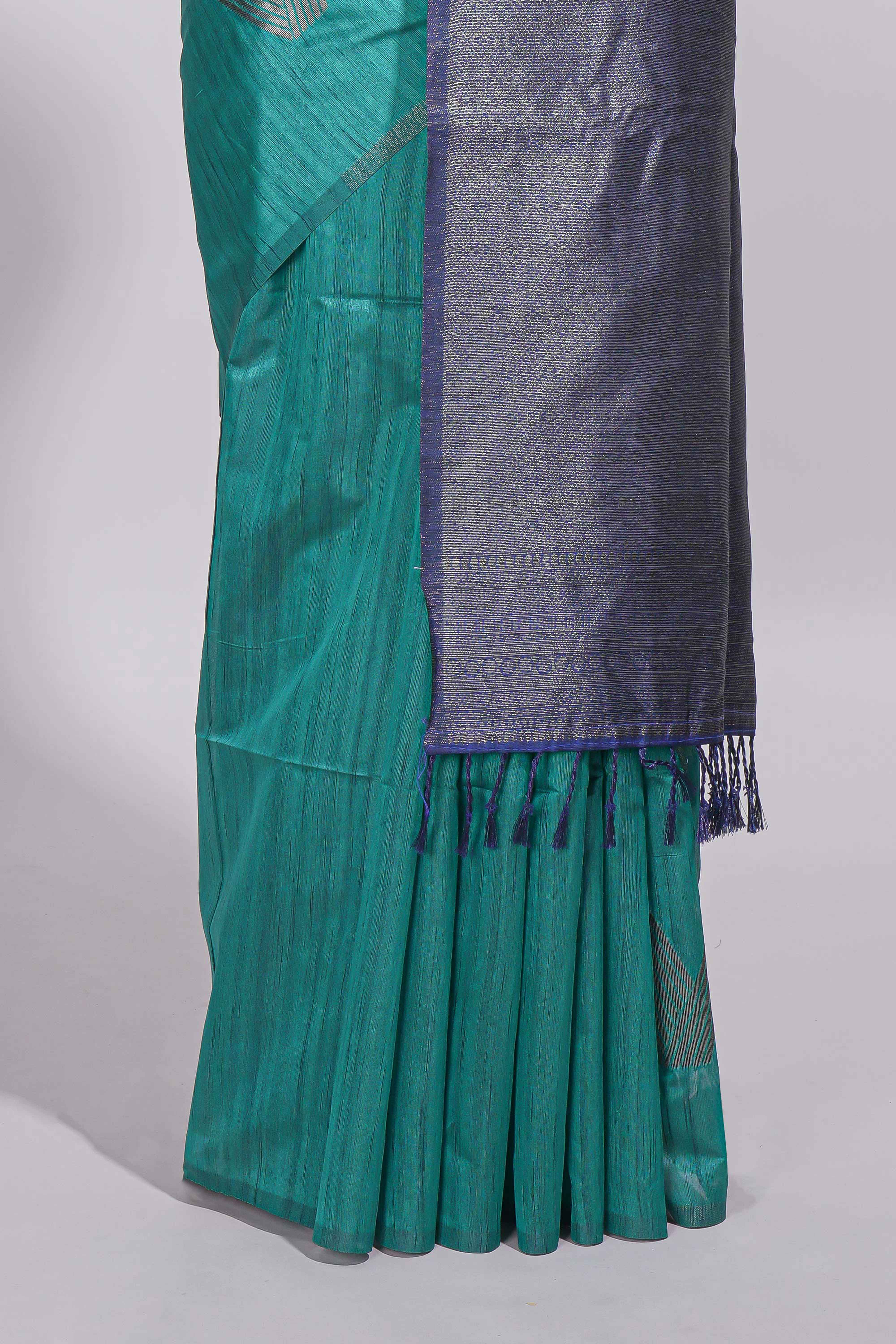 Peacock green tussar saree with subtle silver woven motifs paired with a rich zari pallu with tassels with contrast blouse piece