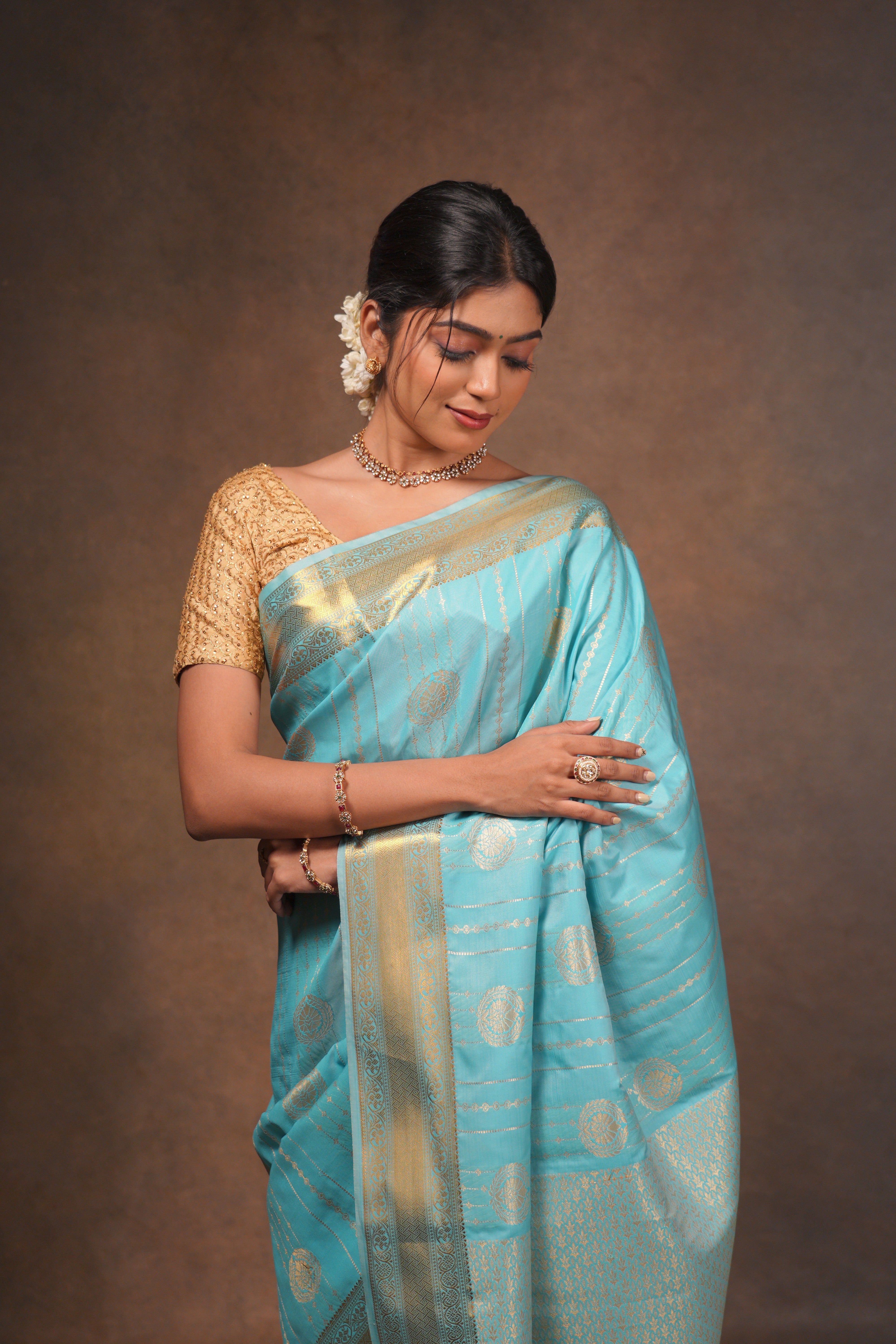 Turquoise blue art silk saree with gold zari woven circular motifs fine vertical zari lines and a rich traditional zari border with woven pallu along with matching blouse