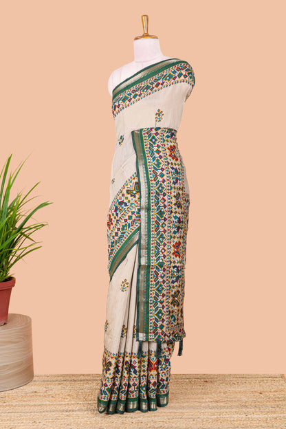 Cream chanderi cotton saree with geometric floral butta, green zari border and patola inspired mirror work