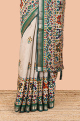 Cream chanderi cotton saree with geometric floral butta, green zari border and patola inspired mirror work
