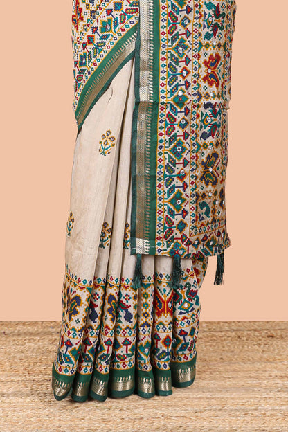 Cream chanderi cotton saree with geometric floral butta, green zari border and patola inspired mirror work