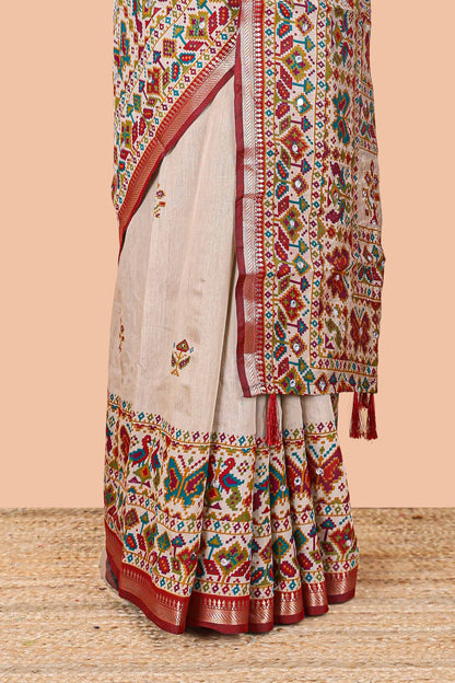 Cream chanderi cotton saree with geometric floral butta, maroon zari border and patola inspired mirror work