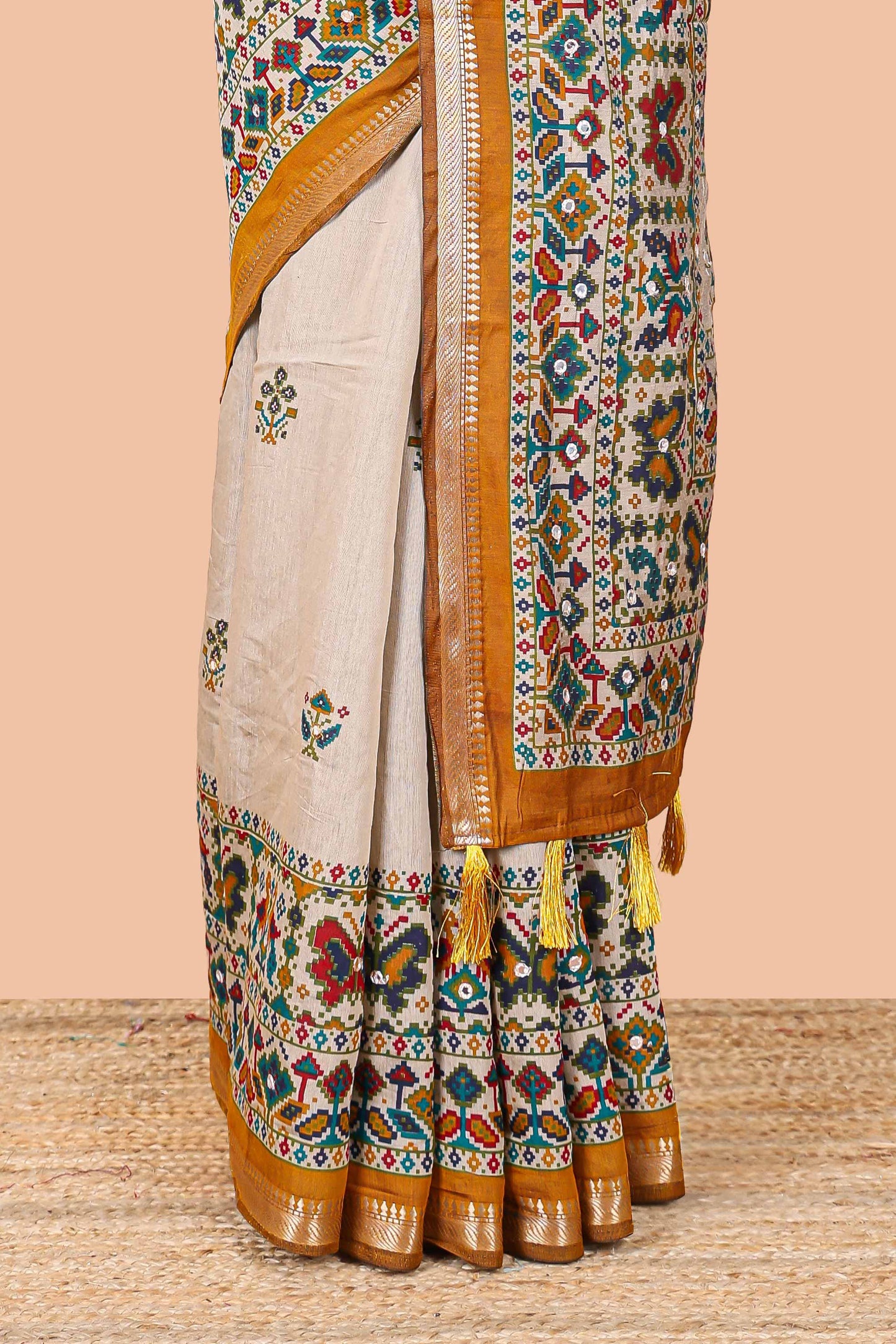 Cream chanderi cotton saree with geometric floral butta, mustard zari border and patola inspired mirror work