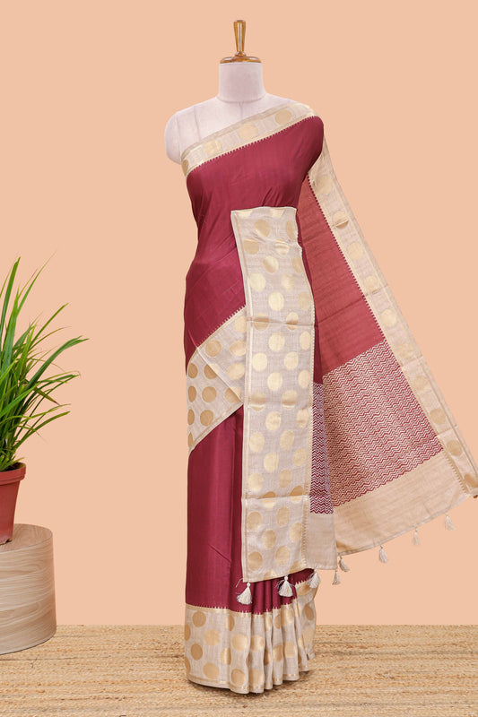 Maroon art tussar saree with plain body, cream coin motif zari border and zig-zag printed pallu
