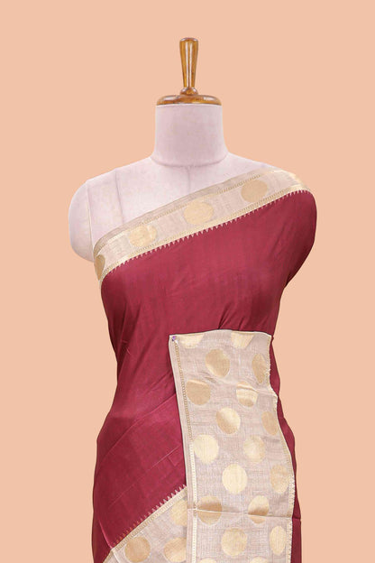 Maroon art tussar saree with plain body, cream coin motif zari border and zig-zag printed pallu