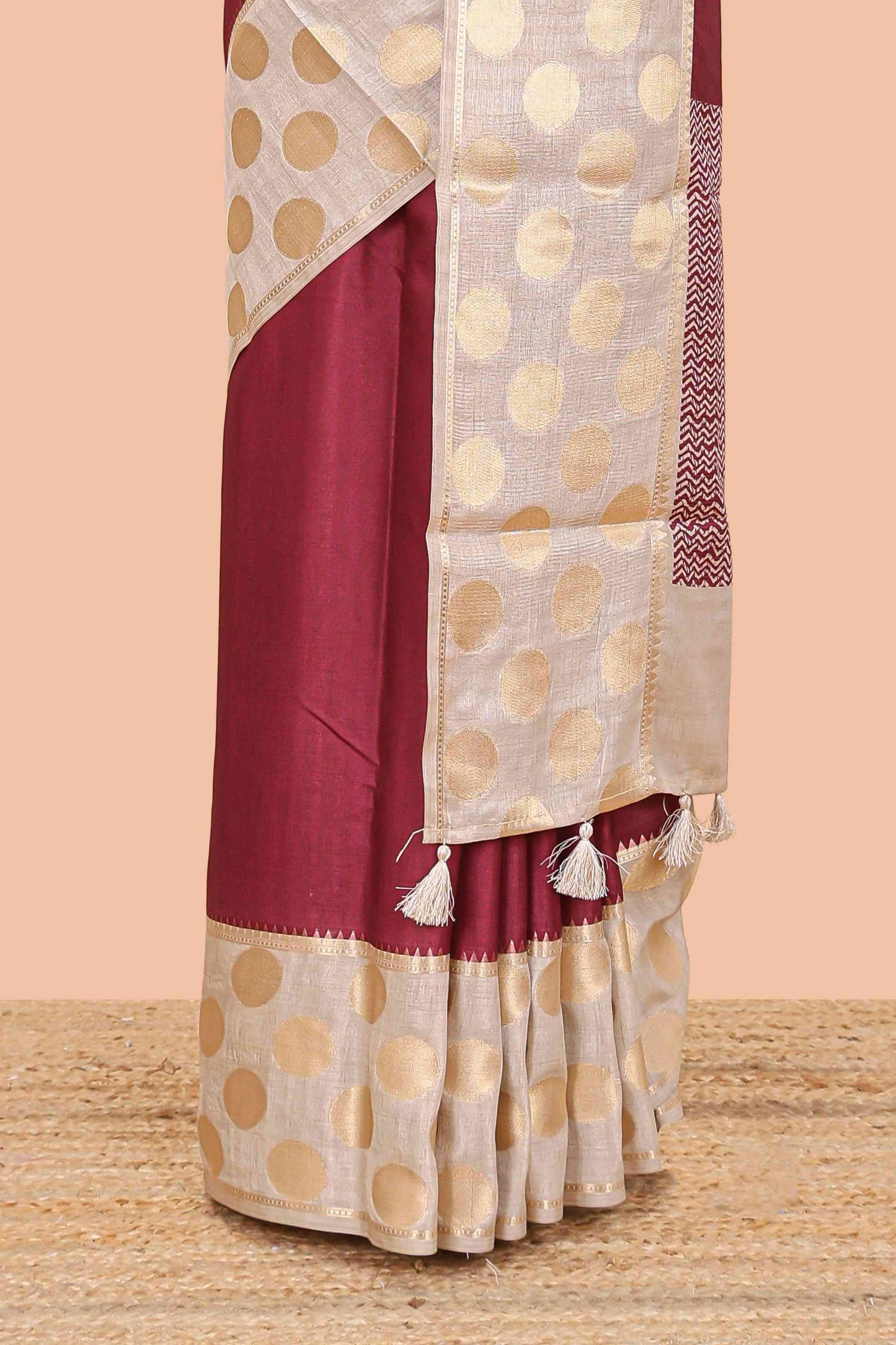 Maroon art tussar saree with plain body, cream coin motif zari border and zig-zag printed pallu