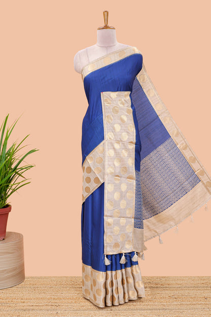 Blue art tussar saree with plain body, cream coin motif zari border and zig-zag printed pallu