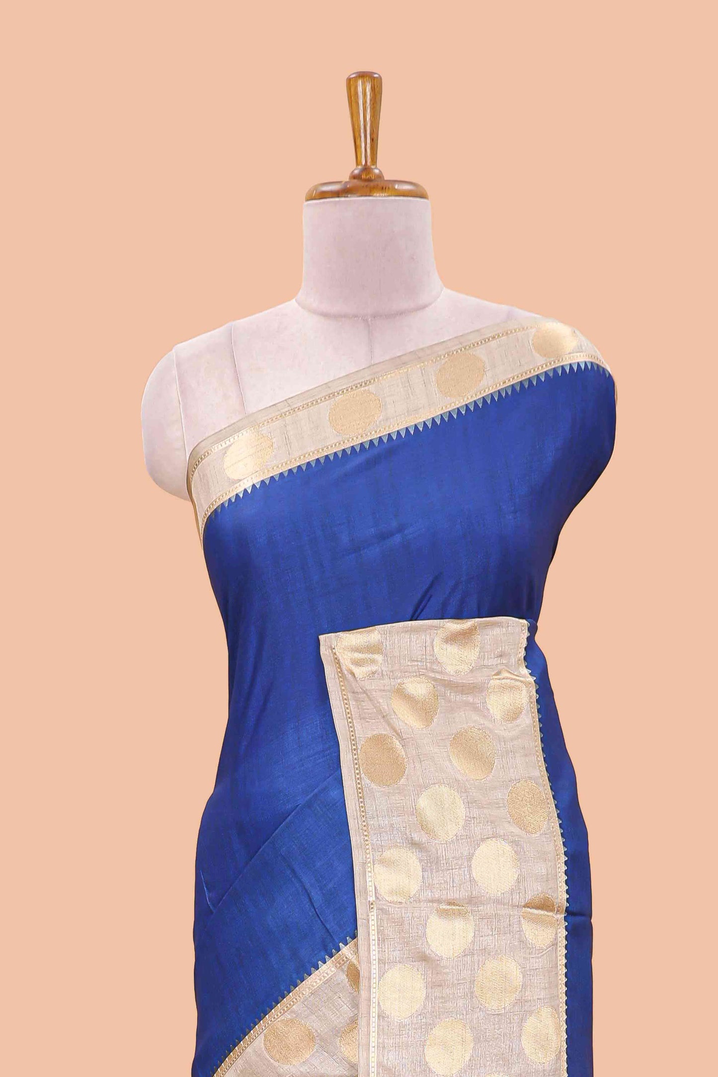 Blue art tussar saree with plain body, cream coin motif zari border and zig-zag printed pallu