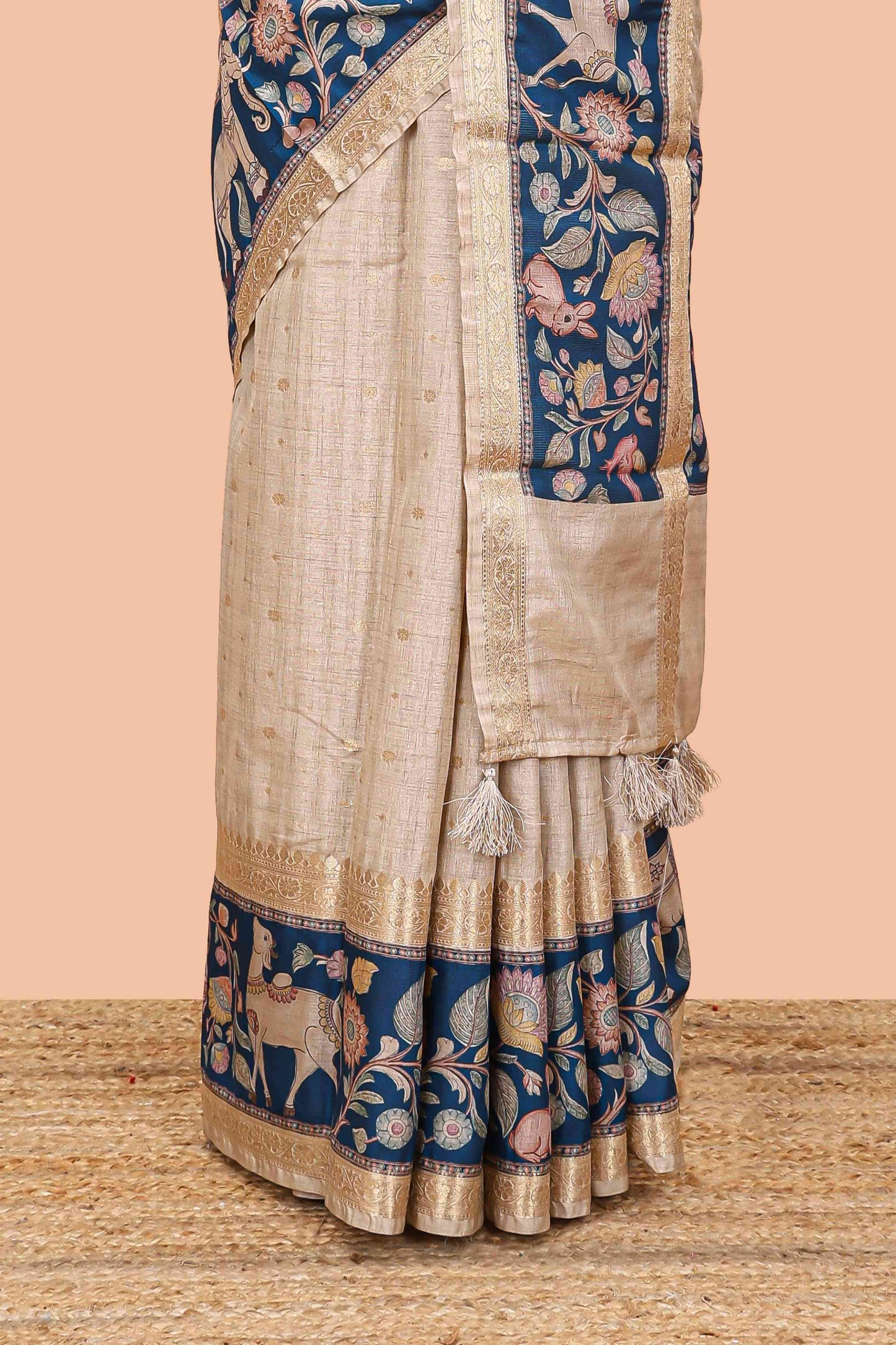Beige art tussar silk saree featuring zari butta and blue retta-patta border with kalamkari animal designs