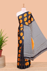 Black satin modal saree with orange polka print, contrast checked pallu, and printed blouse
