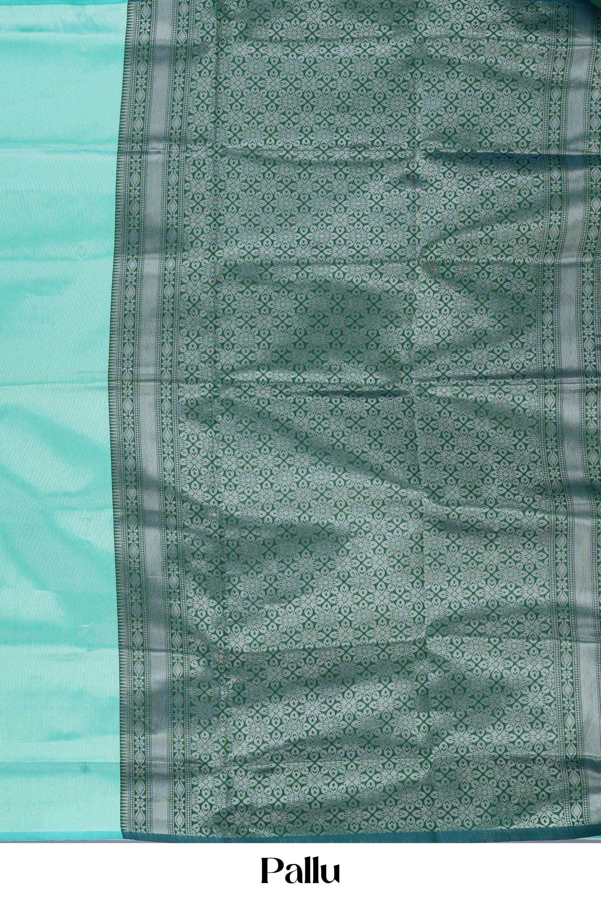 Teal  green lichi silk saree with a patterned pallu on a light blue background 
