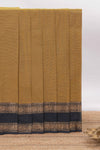 Mustard yellow Chettinad cotton saree with a plain body and a contrasting black border by intricate antique gold zari motifs along with blouse piece