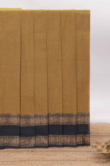 Mustard yellow Chettinad cotton saree with a plain body and a contrasting black border by intricate antique gold zari motifs along with blouse piece