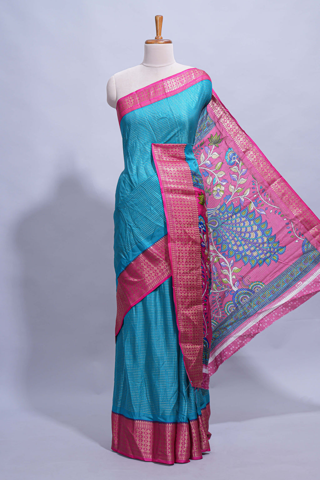 Turquoise blue dola silk saree with fine zari stripes contrast  zari border and a rich peacock floral woven pallu along with printed contrast blouse