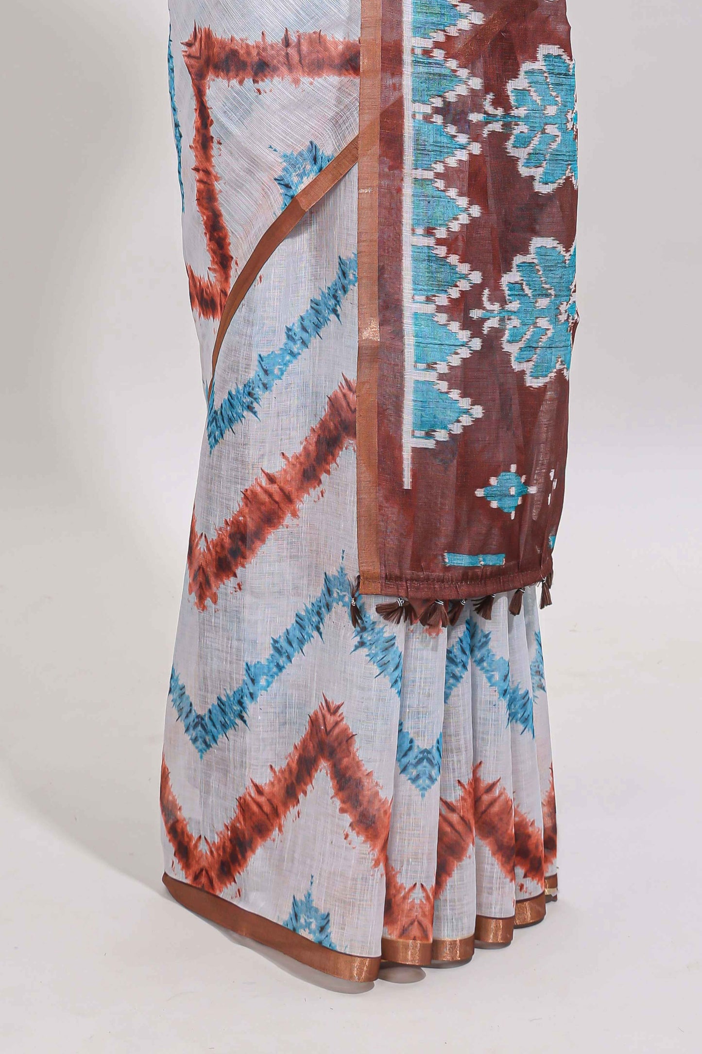 Off white chevron style shibori print linen cotton saree with contrast brown border and ikkat design pallu