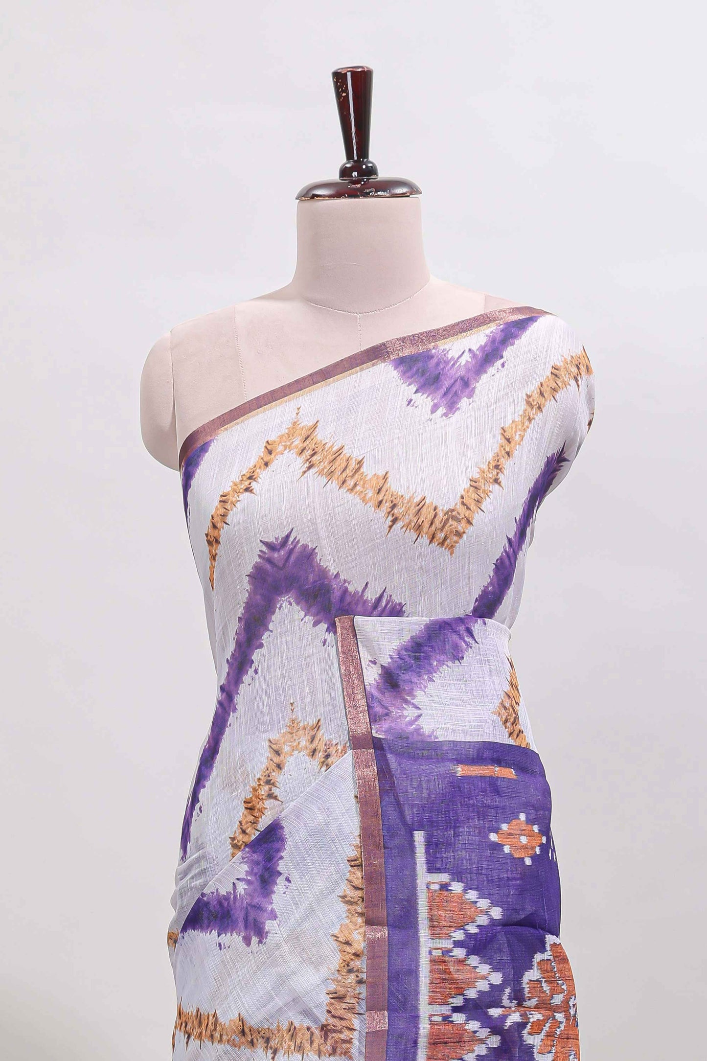 Off white chevron style shibori print linen cotton saree with contrast violet border and ikkat design pallu