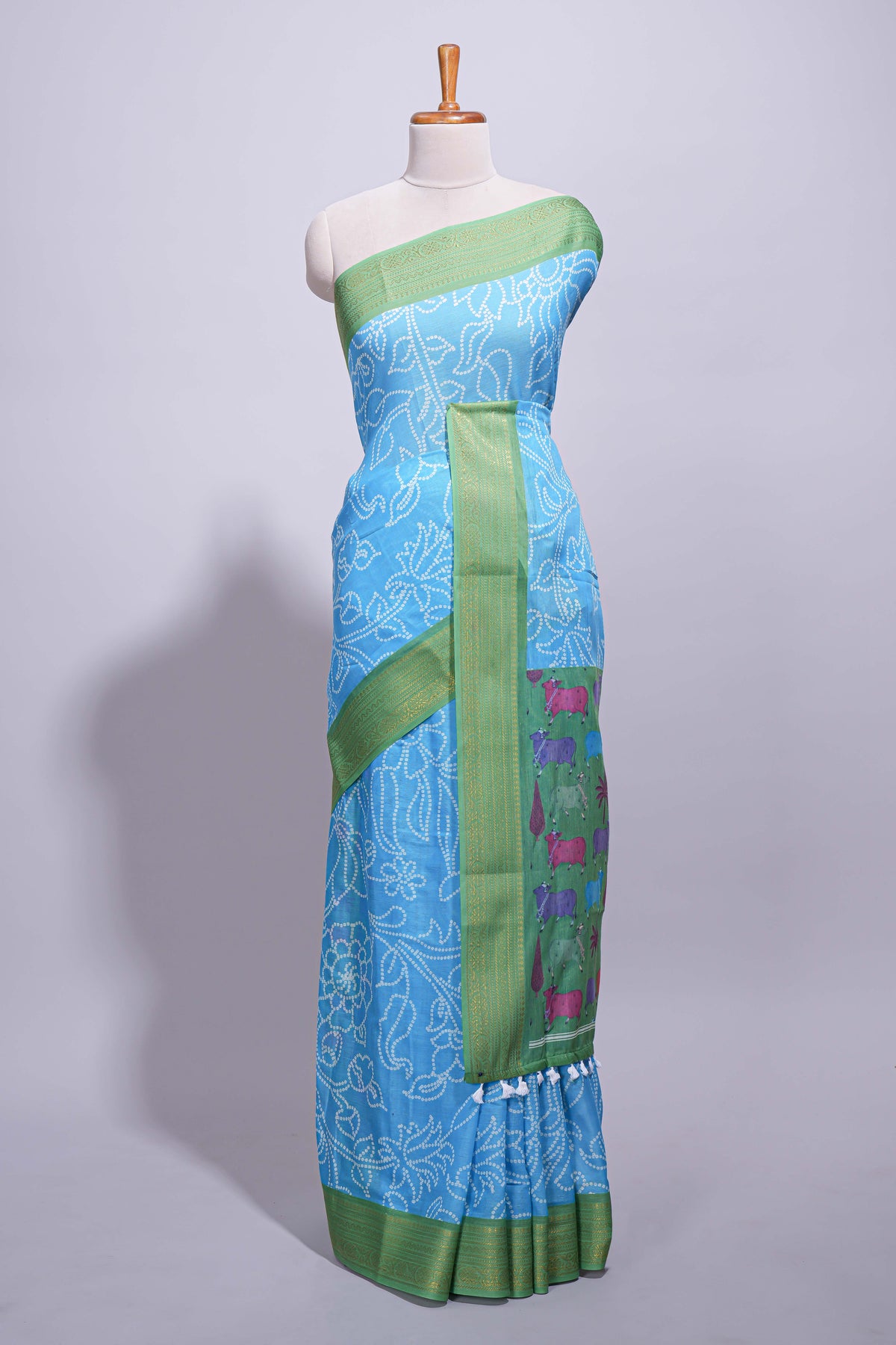Blue linen saree with white dotted floral patterns with golden zari border and a multicolour pichwai motifs along with printed blouse